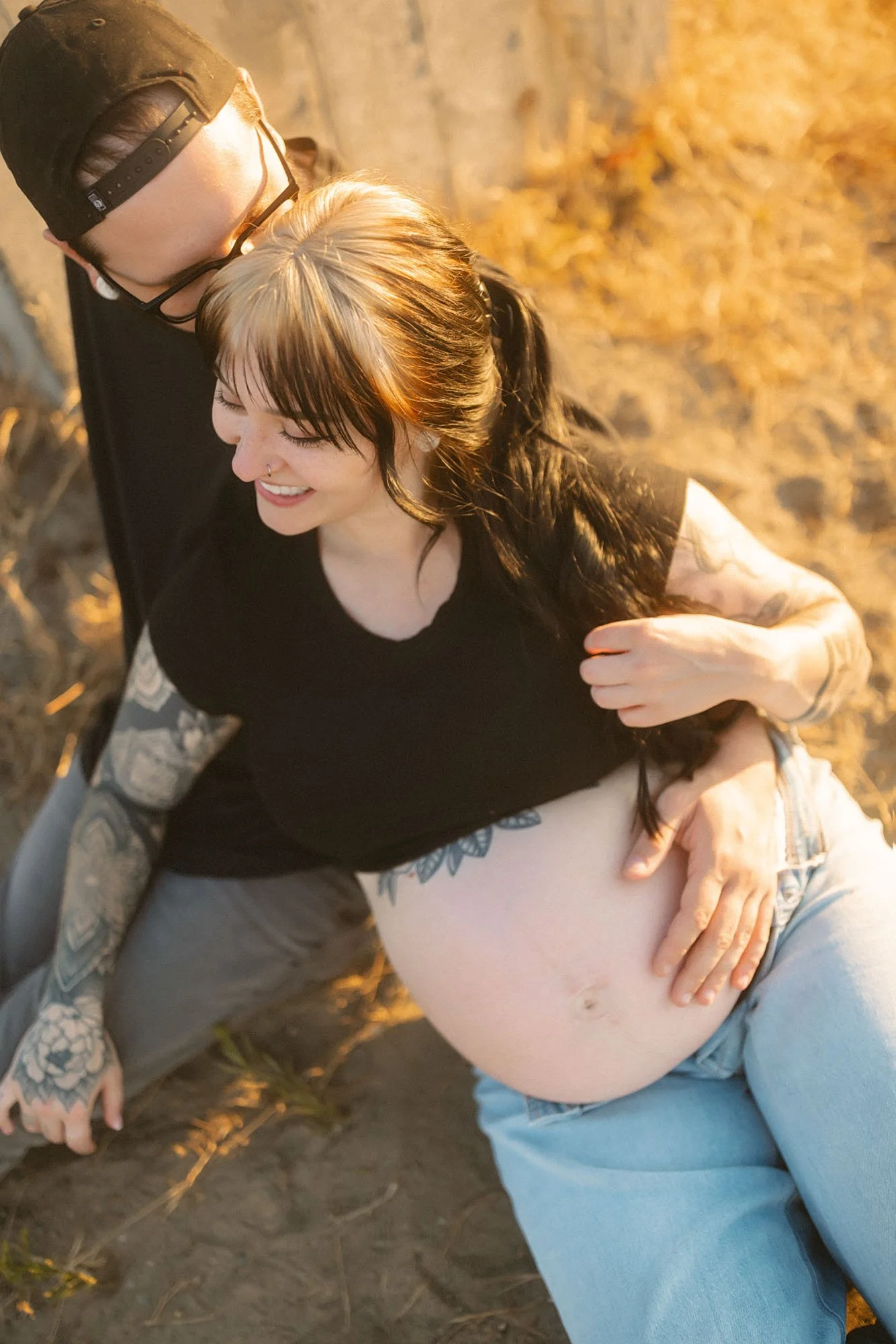 Expectant parents relaxing together in a grassy field during a golden-hour maternity session in Tacoma.