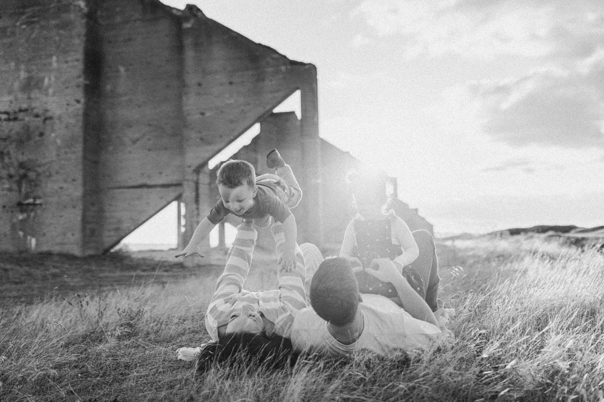Candid outdoor family photography session with parents and children playing in a grassy field near Tacoma, Washington.