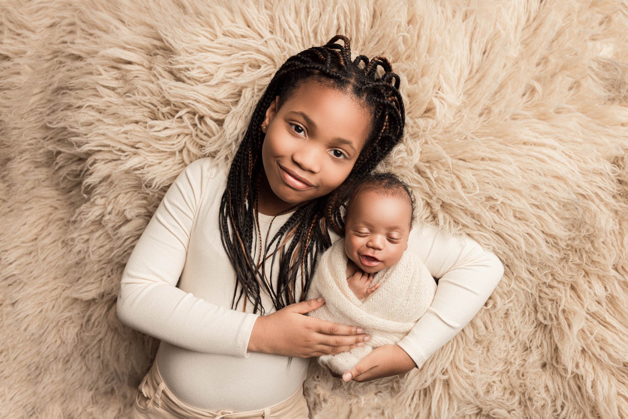 Older sister cuddling her newborn sibling during a Seattle newborn photography session.