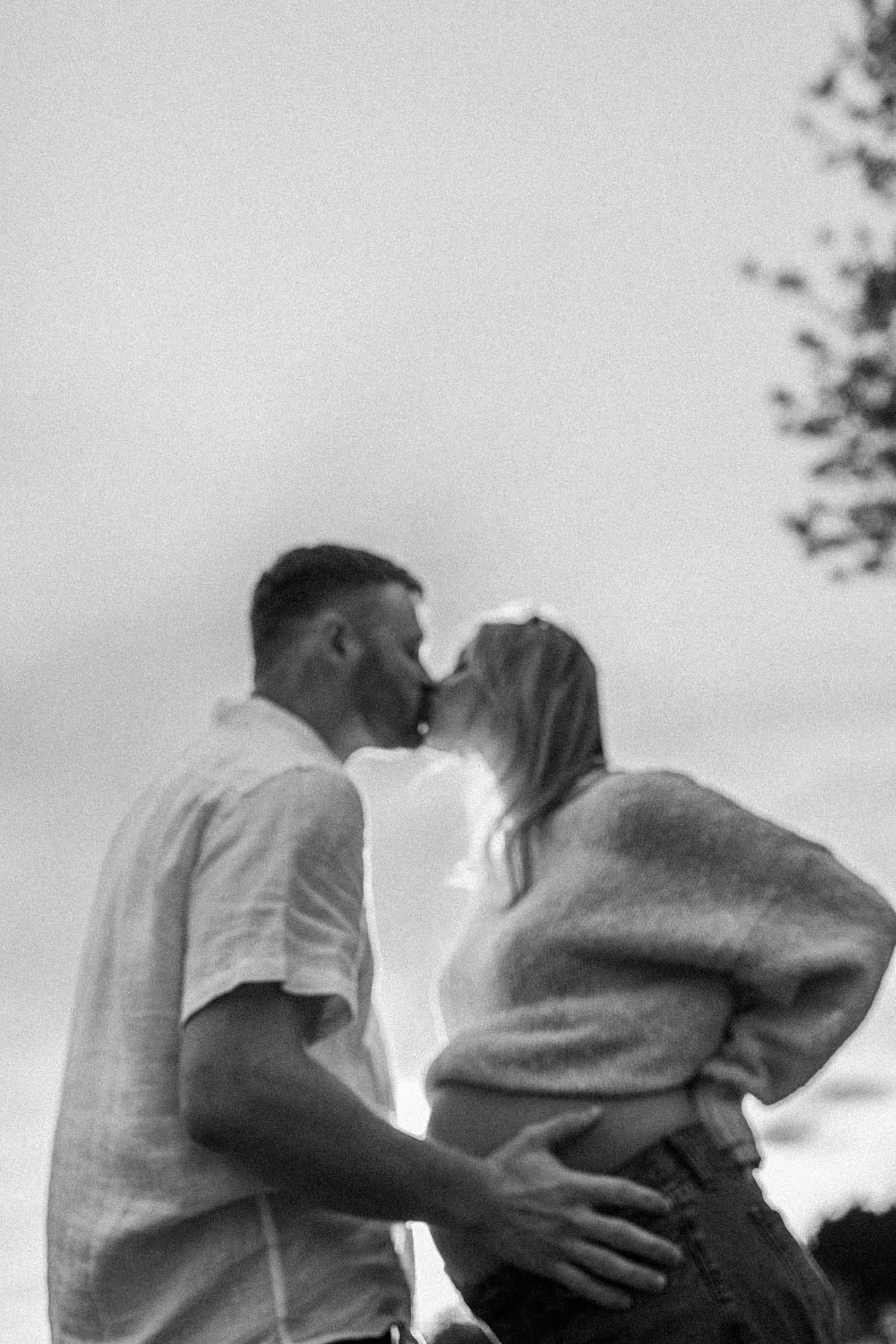 A soft, dreamy kiss captured in motion at Discovery Park, Seattle, creating an emotional and artistic maternity moment.