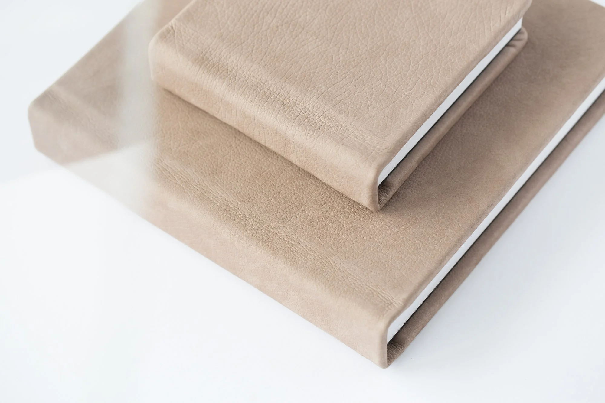 Stacked heirloom leather albums showcasing fine art newborn photography prints offered by Seattle newborn photographer Atsumi Sullivan.