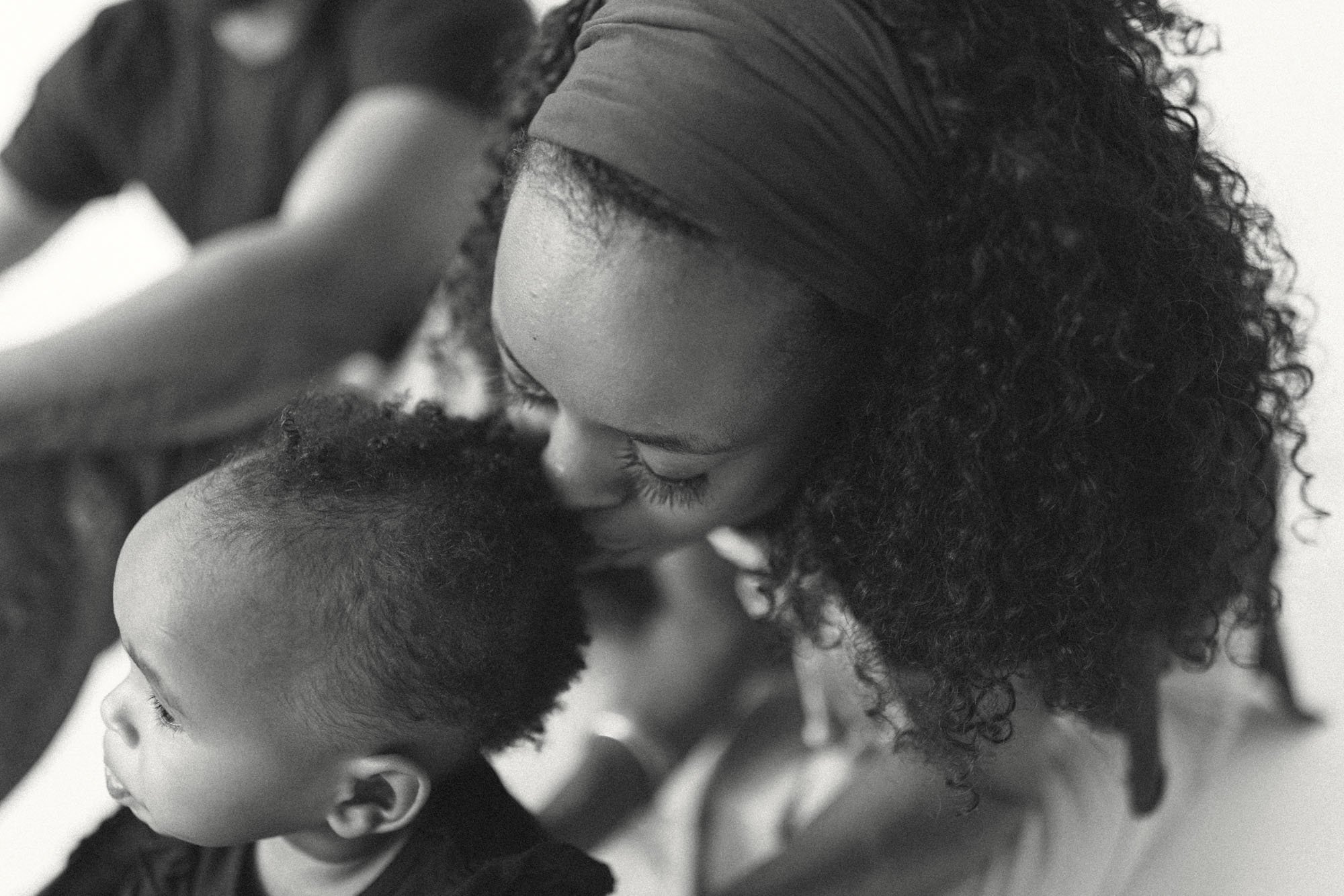 Close-up black and white portrait of a mother kissing her baby’s head, captured during a Seattle lifestyle family session. Emotional, intimate moment highlighting motherhood, connection, and natural studio photography
