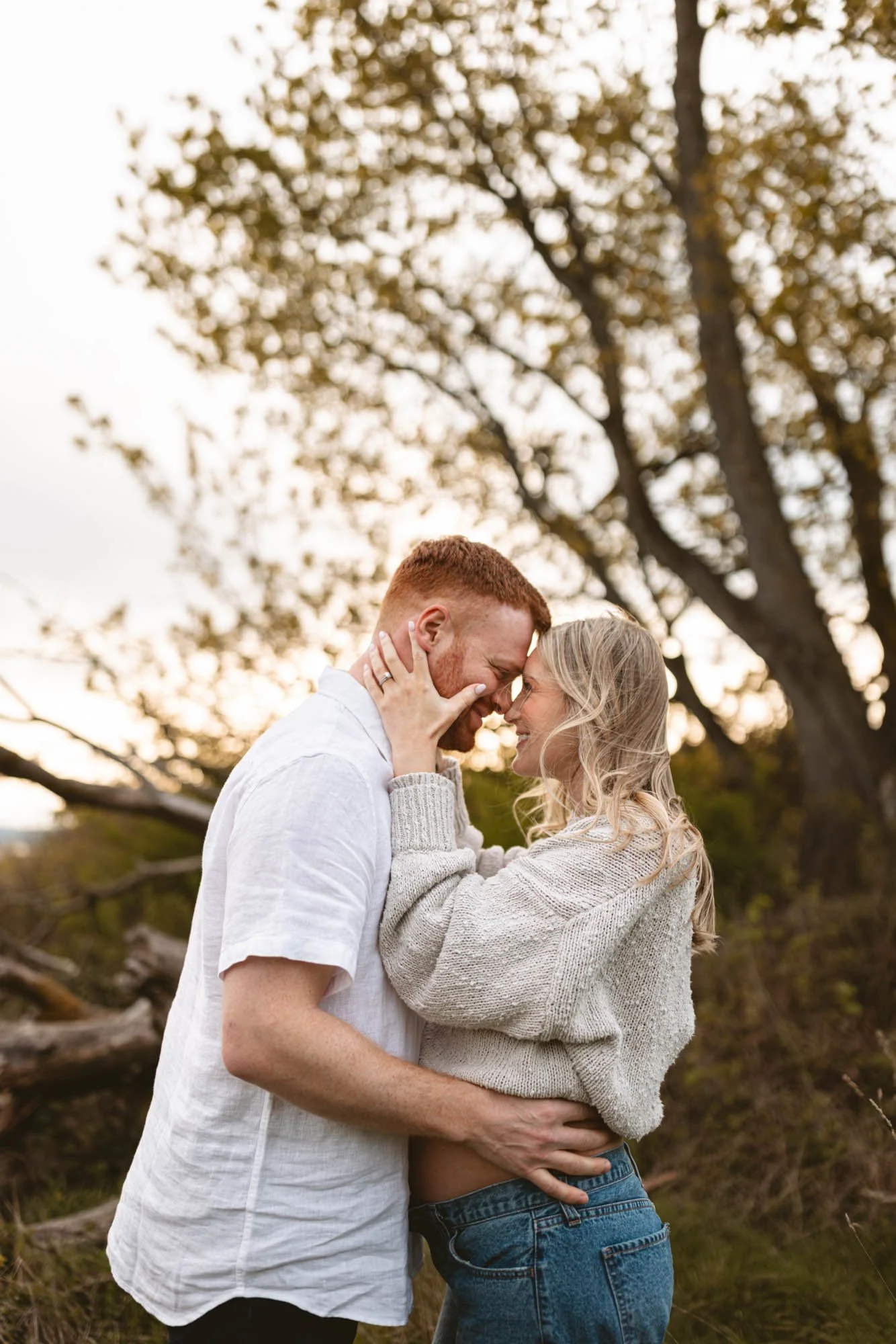 Expecting couple sharing an intimate embrace under golden light at Discovery Park, Seattle, highlighting connection, warmth, and anticipation.
