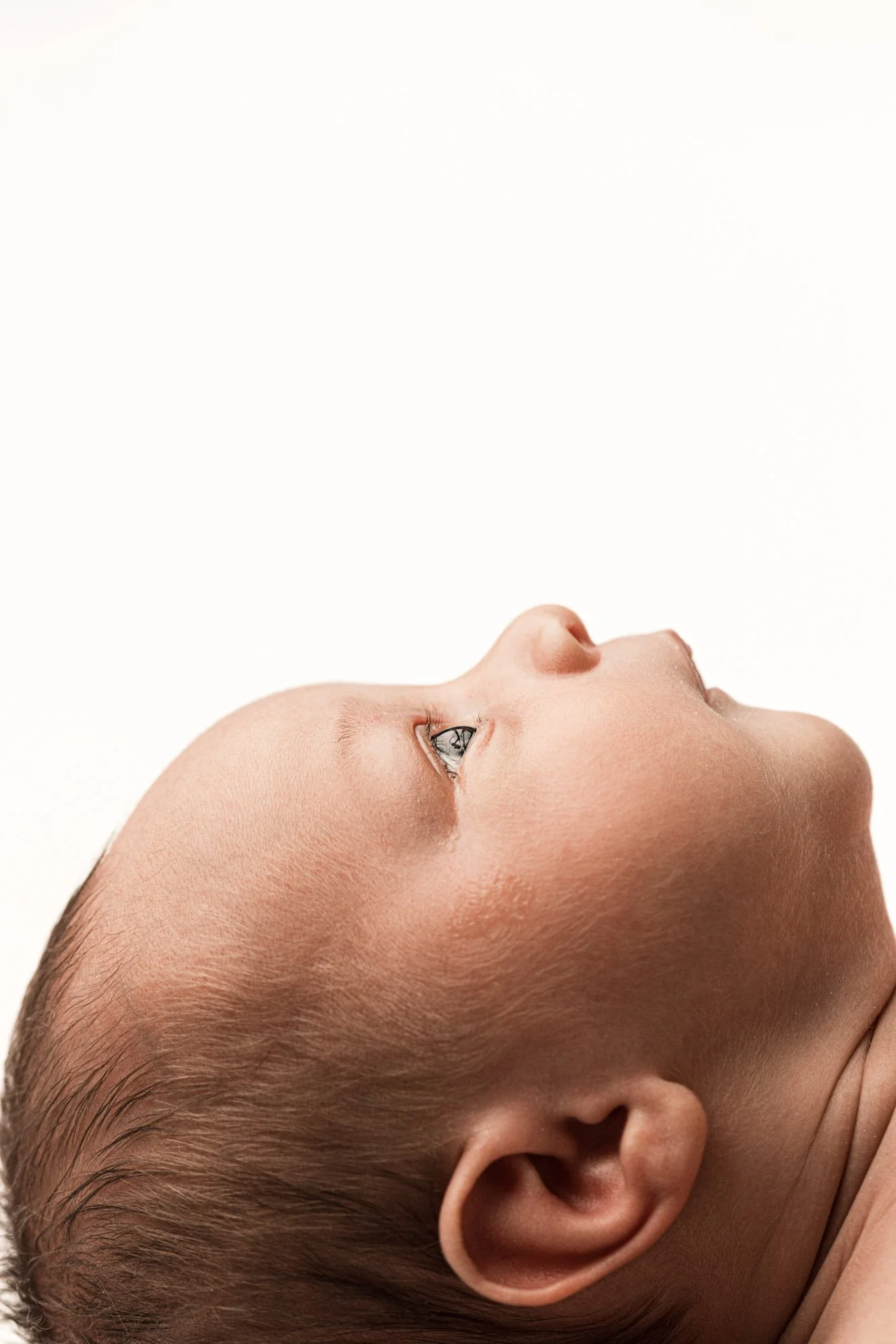 Close-up profile portrait of an awake newborn baby looking upward