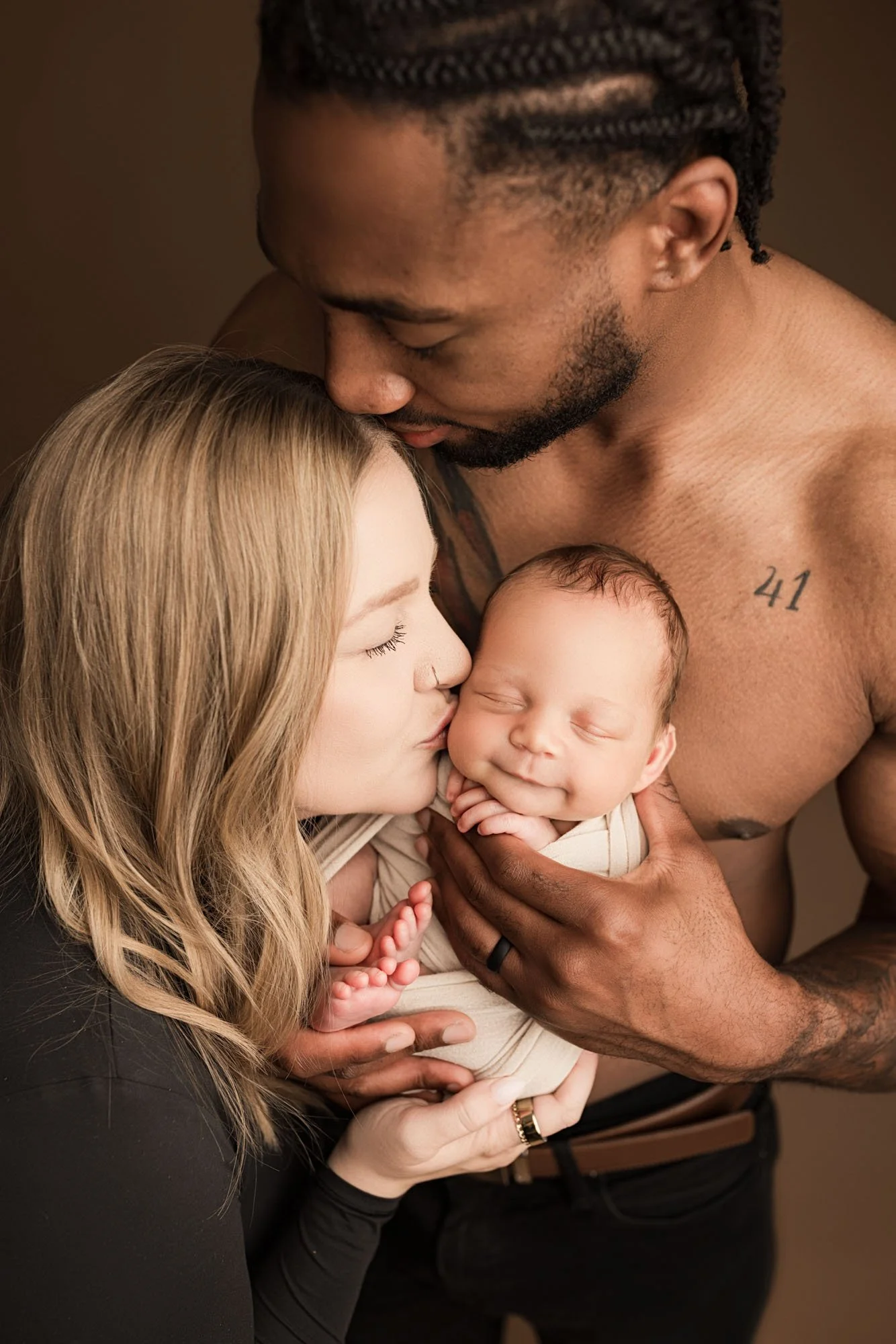 Mother and father lovingly holding their newborn baby during a studio session