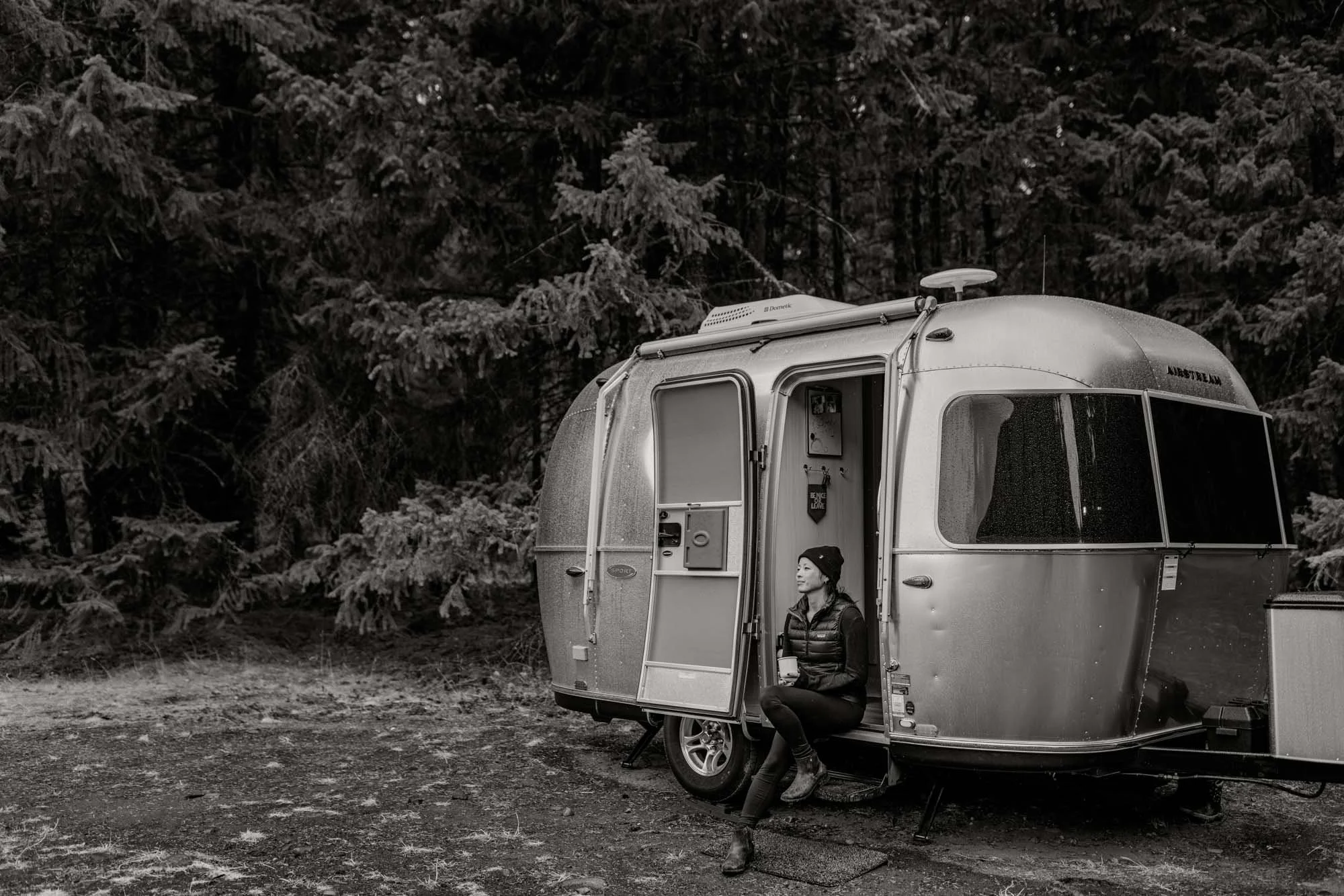 Atsumi Sullivan newborn and family photographer based in Lake Tapps Washington sitting outside an Airstream trailer in the forest