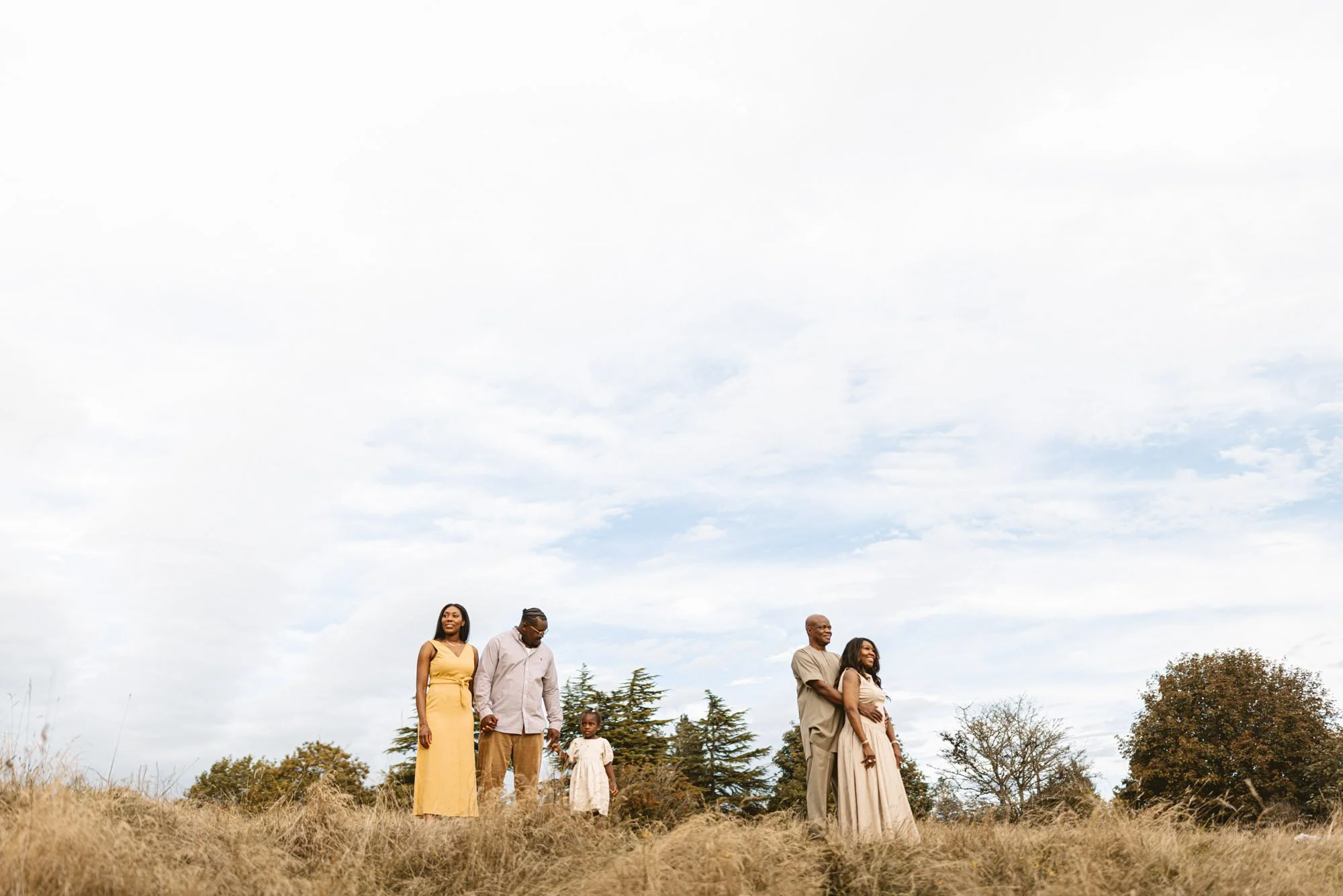 Multigenerational family enjoying an outdoor photography session at Discovery Park in Seattle, surrounded by open fields and soft natural light