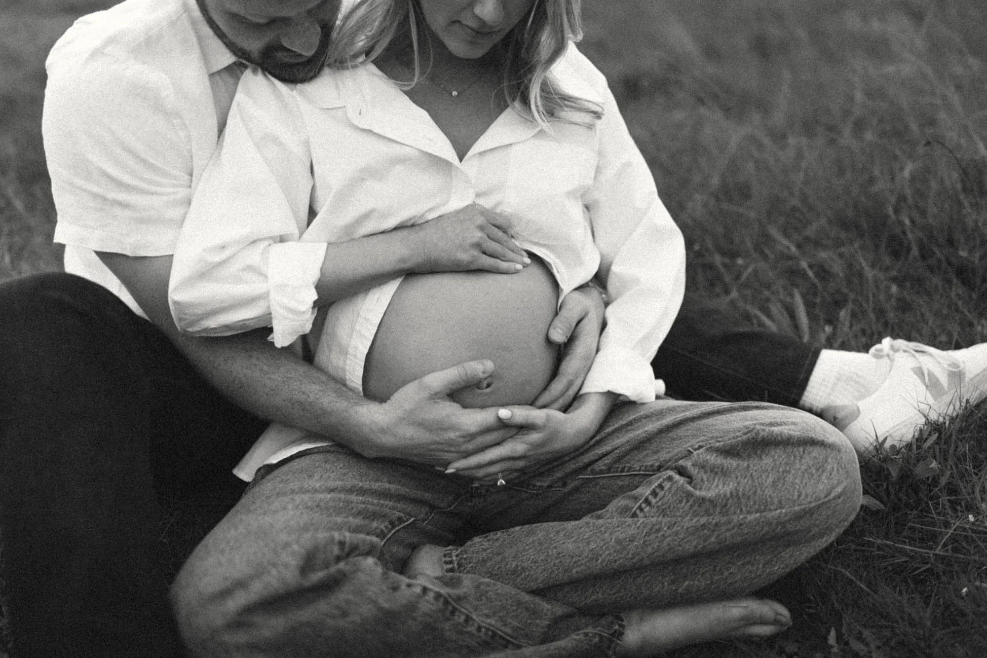 Close-up of expecting parents’ hands resting on baby bump, capturing intimate details and connection during a maternity session in Seattle.
