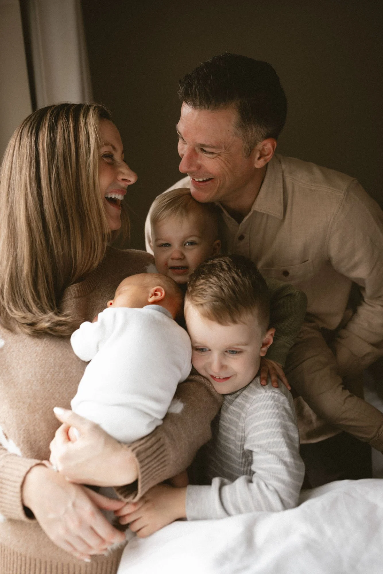 Parents and siblings cuddle their newborn during a cozy in-home lifestyle newborn family photography session in Seattle.