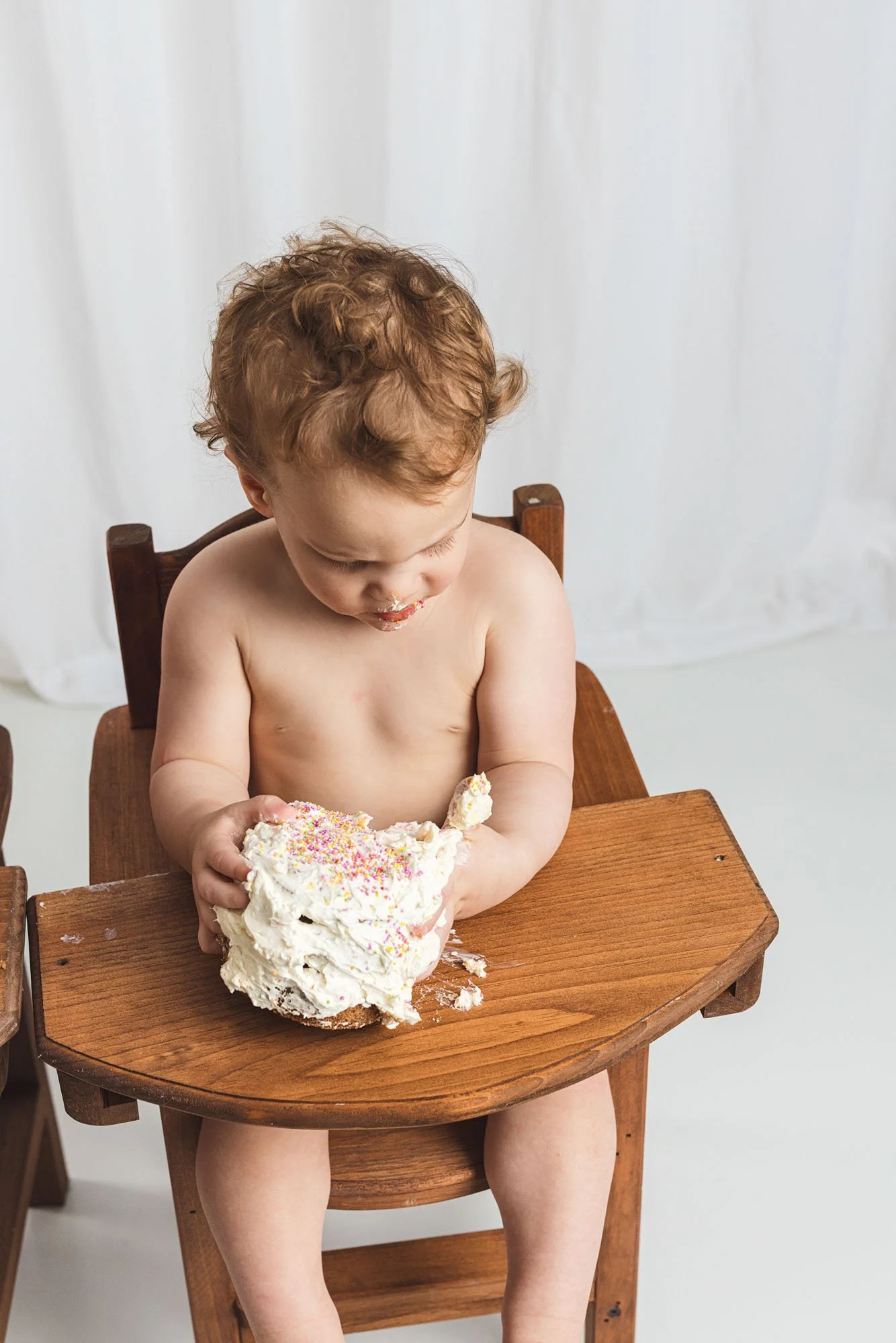 Baby tasting frosting for the first time during a cake smash photography session in Seattle