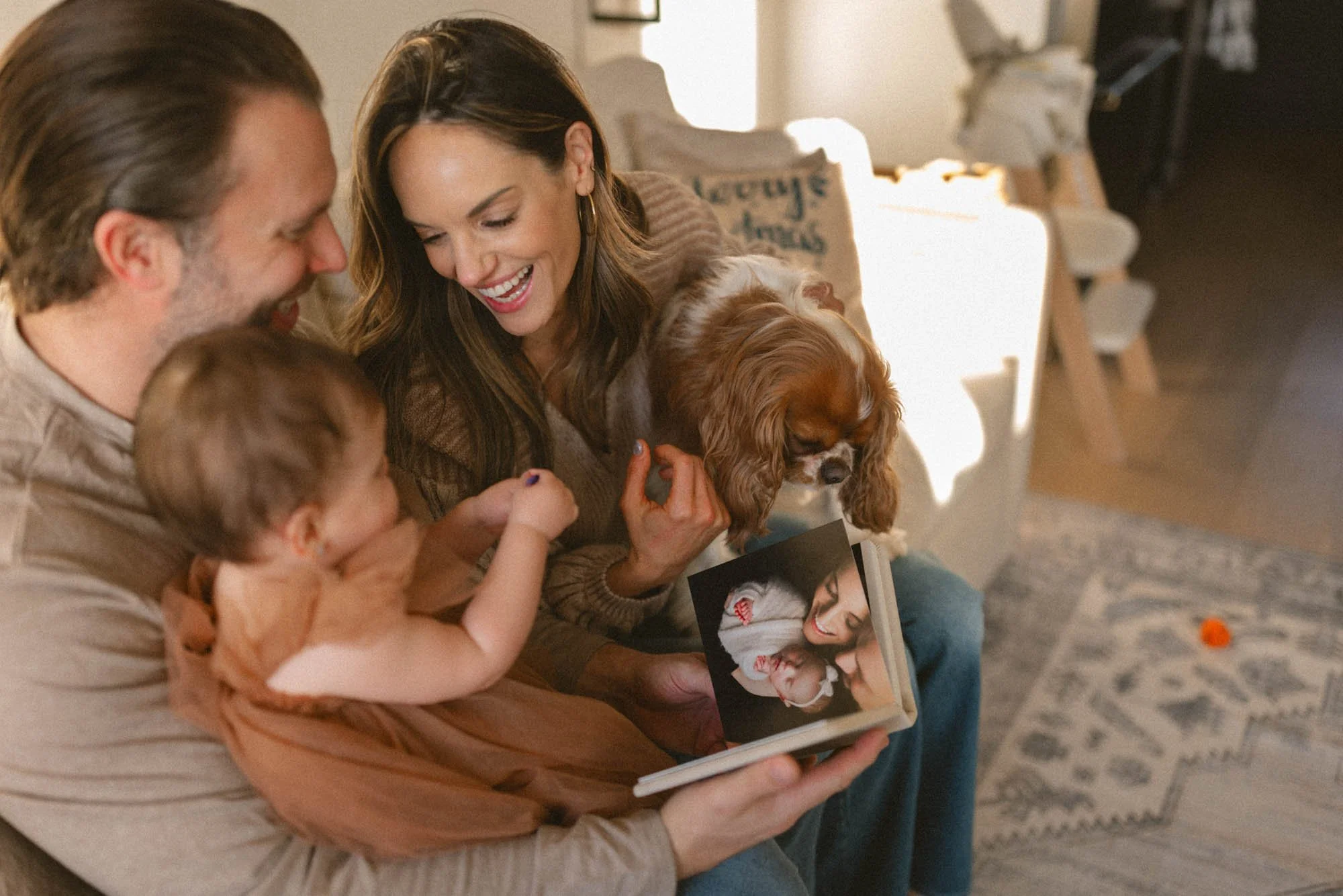 Family at home looking through their newborn heirloom album together with their baby and dog during a Seattle lifestyle family photography session by Atsumi Sullivan.