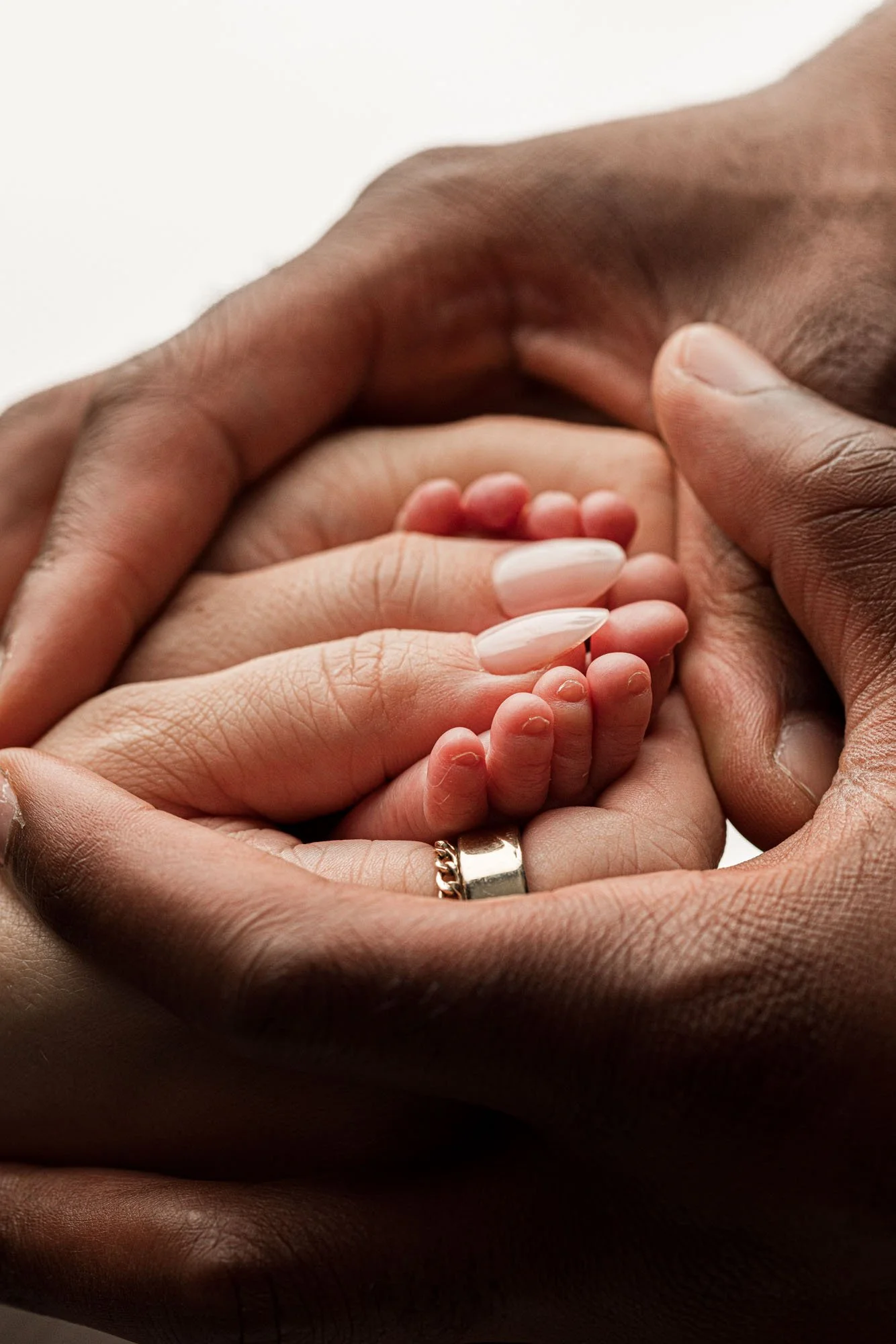 Close-up of a newborn baby’s tiny feet cradled in both parents’ hands