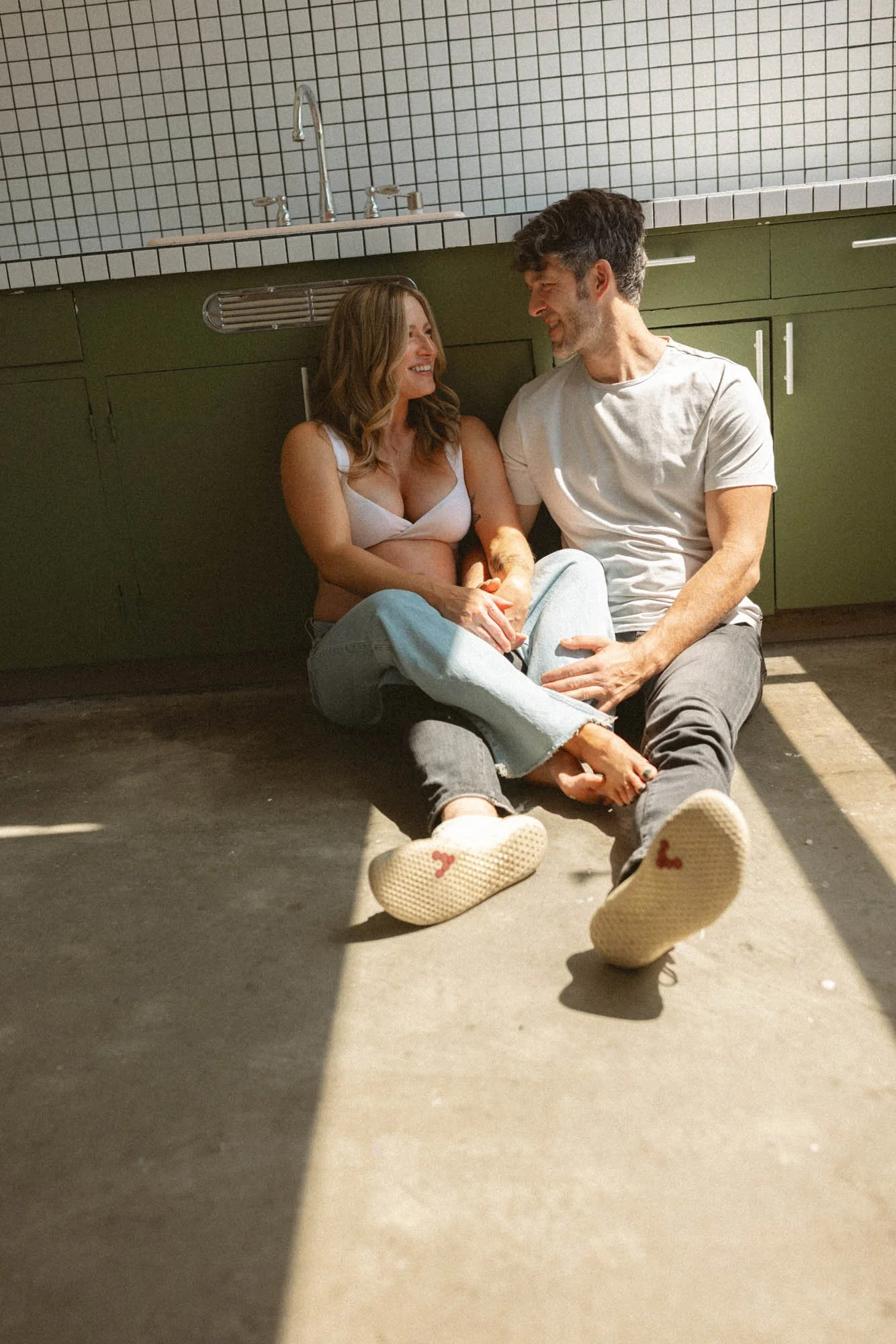 Expecting couple sitting together in warm natural light during a lifestyle maternity photoshoot at a Seattle studio.
