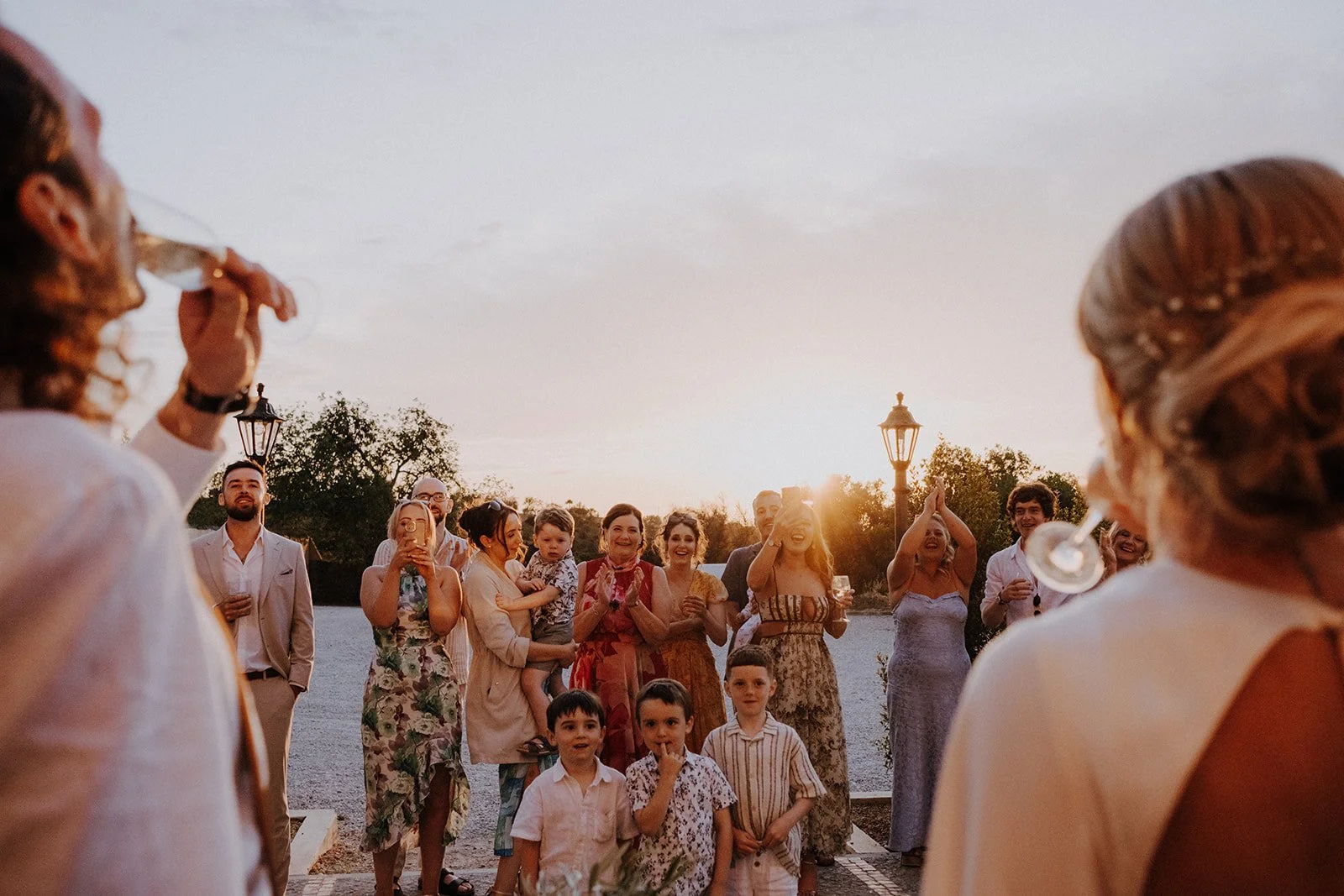 A group of people, gathered outdoors during sunset, celebrating and drinking wine or champagne. Solar do Paço.
