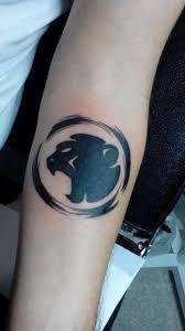 Tattoo of a stylized black Cheeky Monday monkey inside a circular border on a forearm.