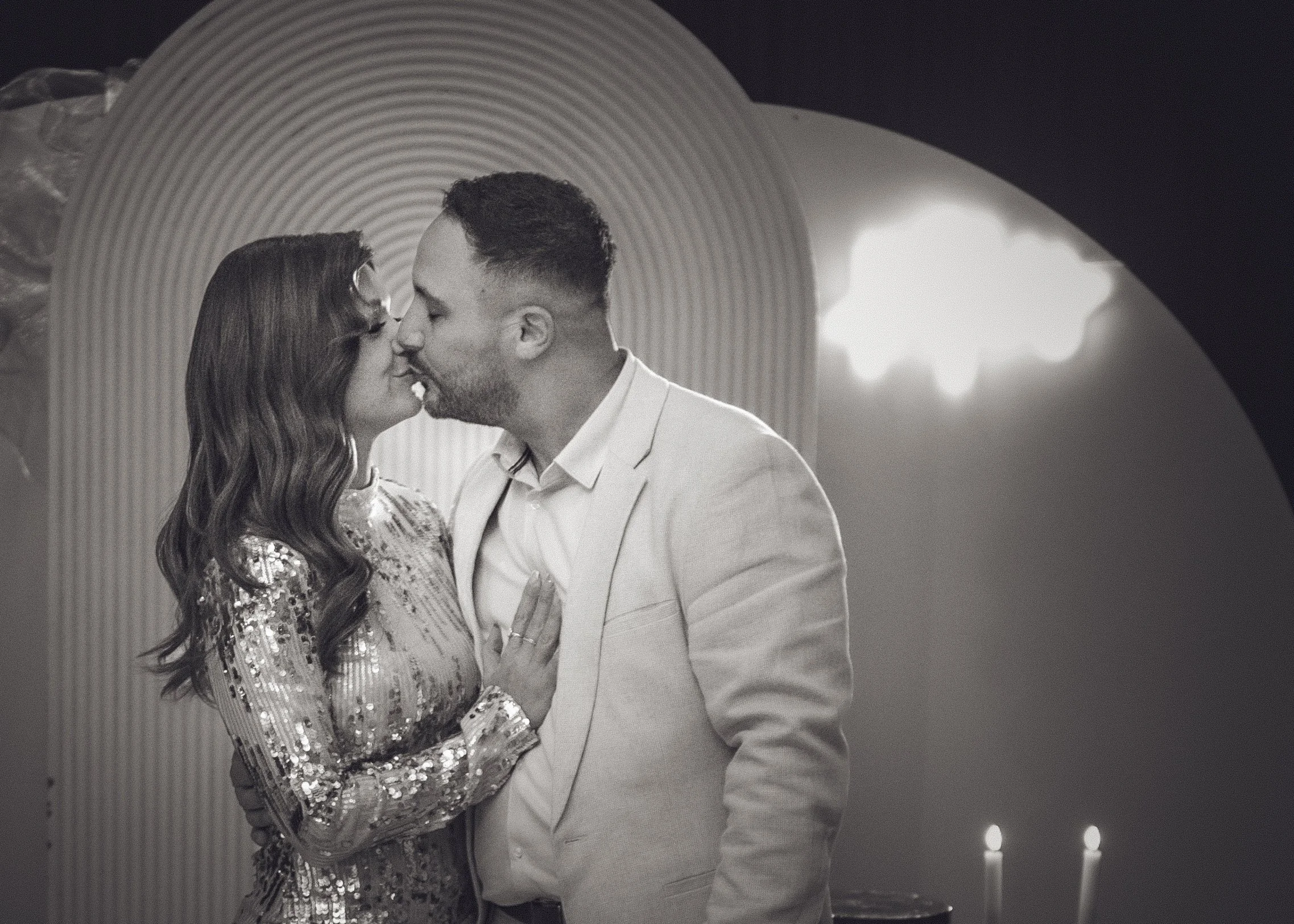 A couple sharing a kiss at an intimate event, with candles and decorative lights in the background. yarra valley and Melbourne wedding photographer