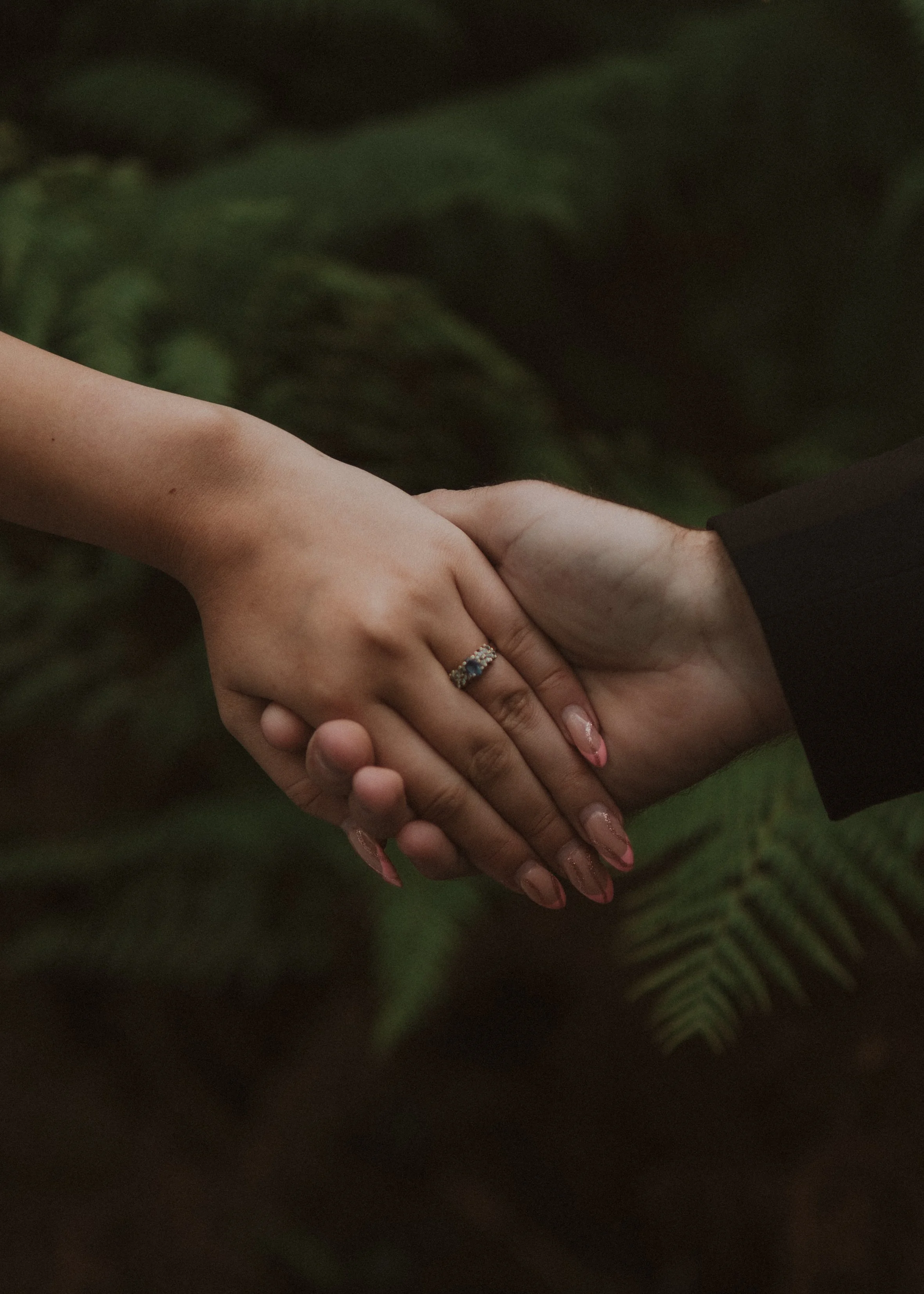 Close-up of two hands shaking, one hand wearing a wedding ring, with a green leafy background. yarra valley and Melbourne wedding photographer