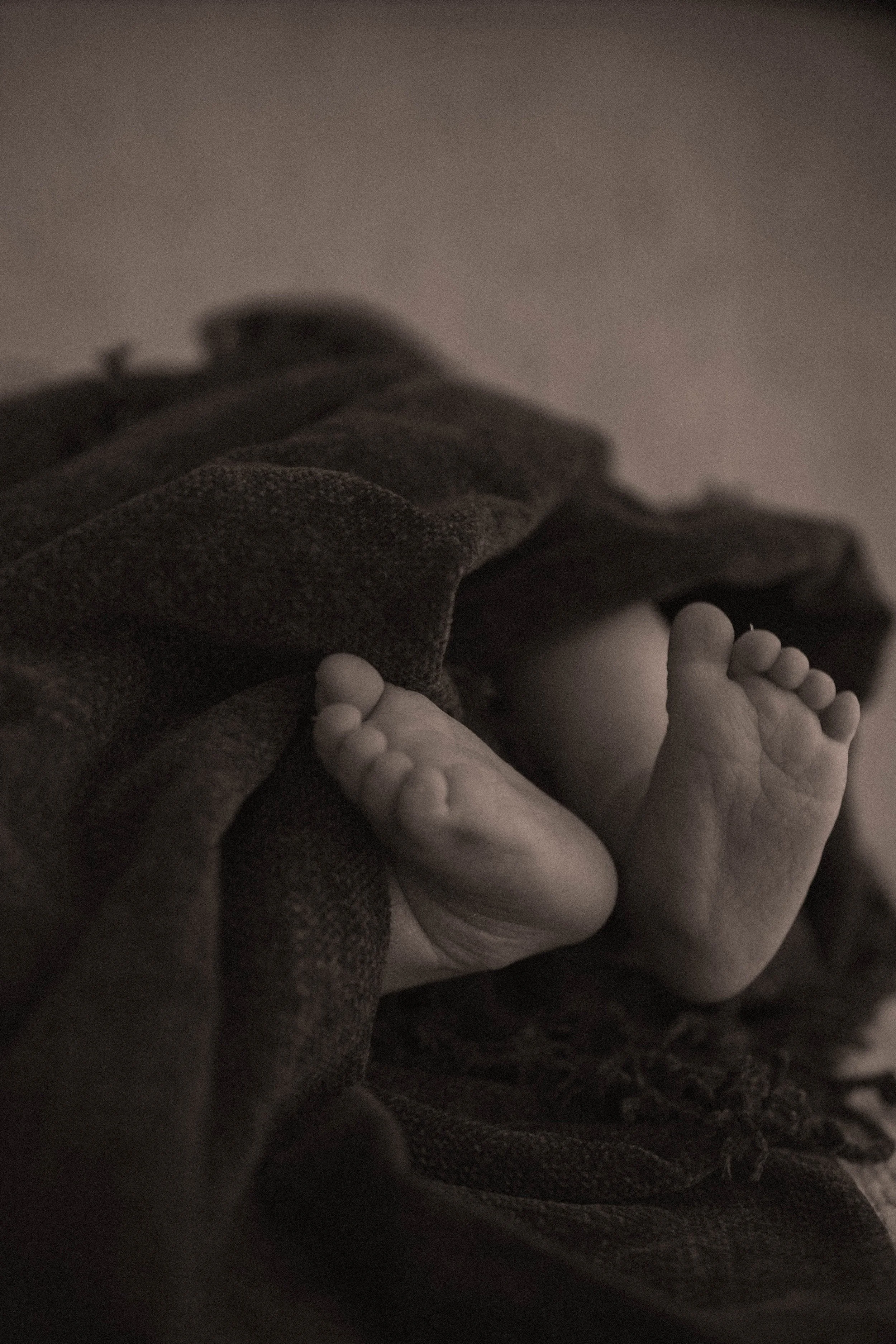newborn baby in whittlesea studio little black and white toes poking out of a warm cozy blanket