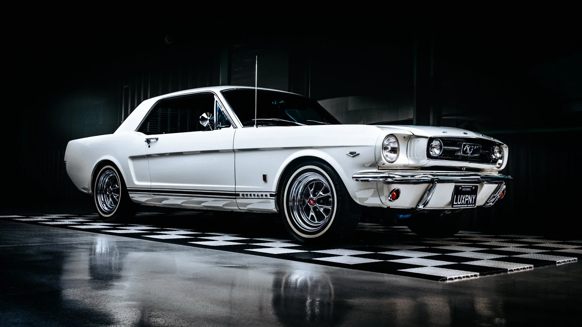 Vintage white Ford Mustang on display in a dimly lit showroom with a reflective checkered floor.