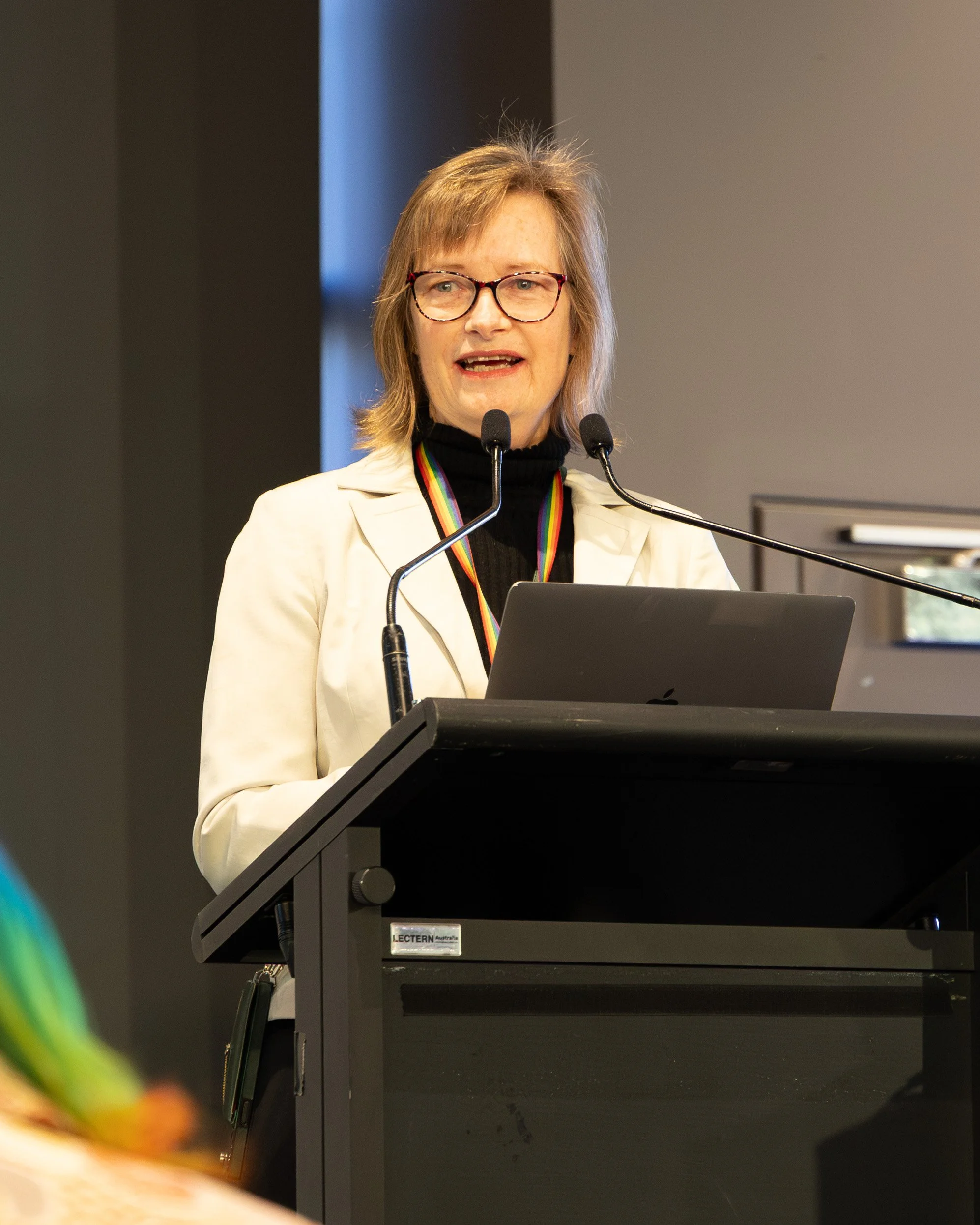 A colour image of a woman behind a lectern at a business event 
