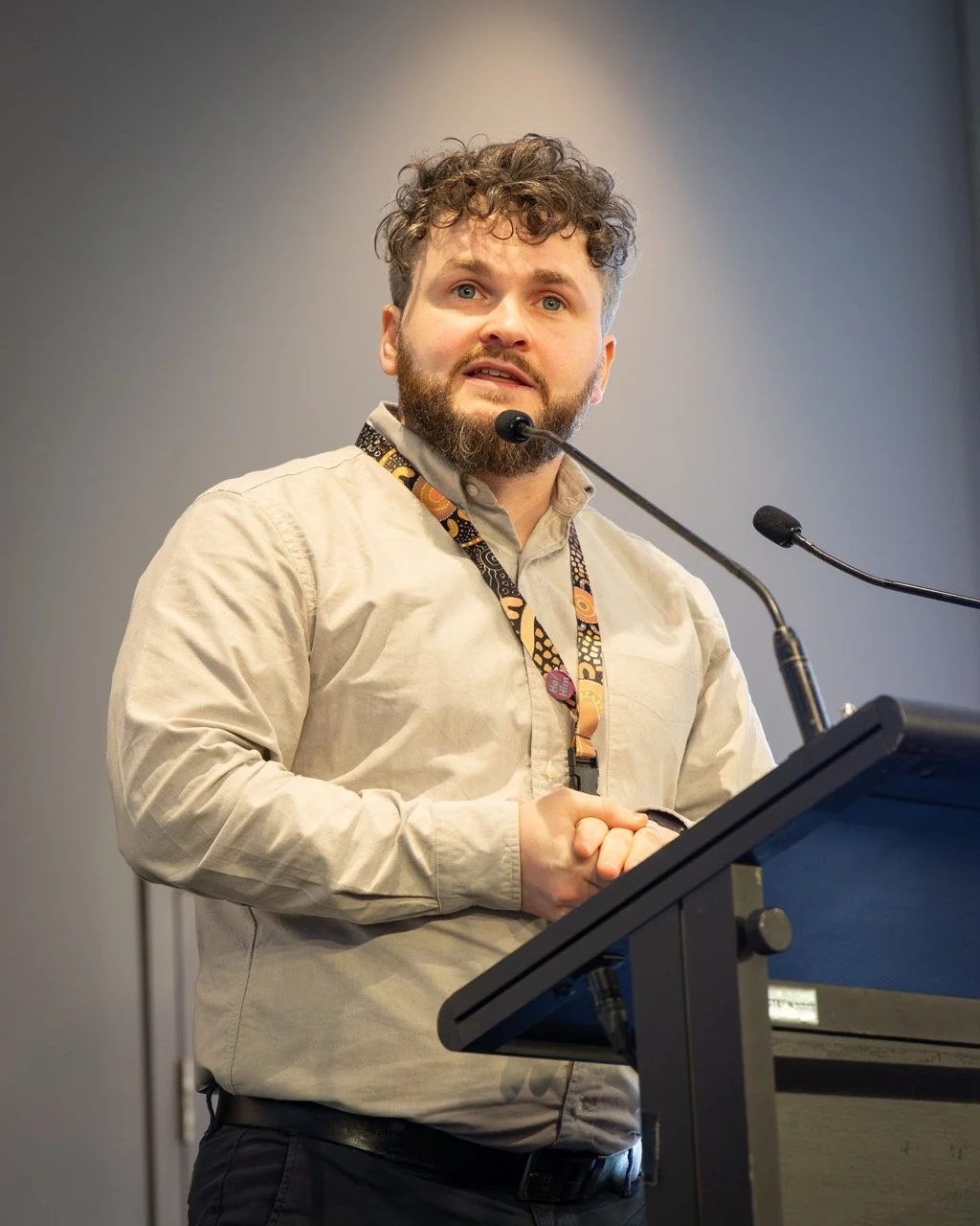 A colour image of a man behind a lectern at a business event 
