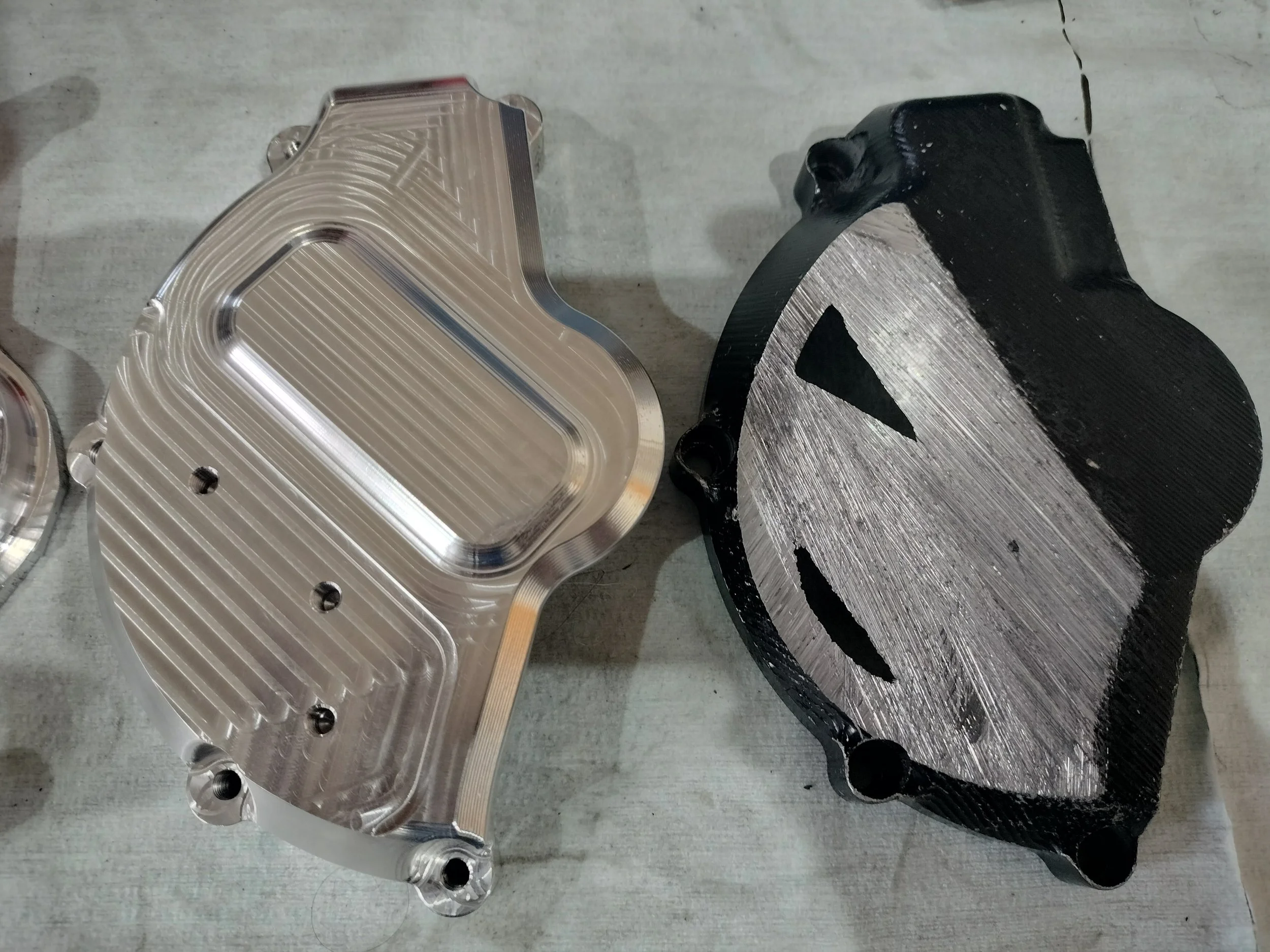 Parti meccanici di un motore, uno in metallo lucido e l'altro verniciato nero con superficie lavorata.