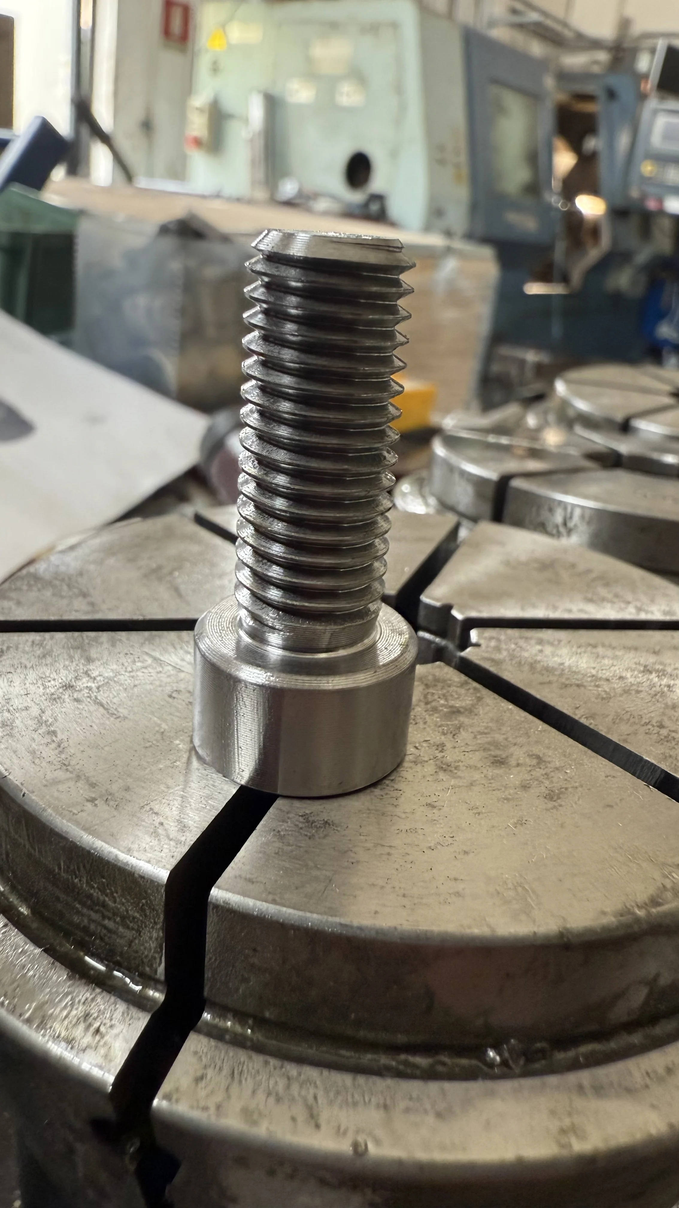 Vite in acciaio inox su una tavola di lavoro in un'officina meccanica.