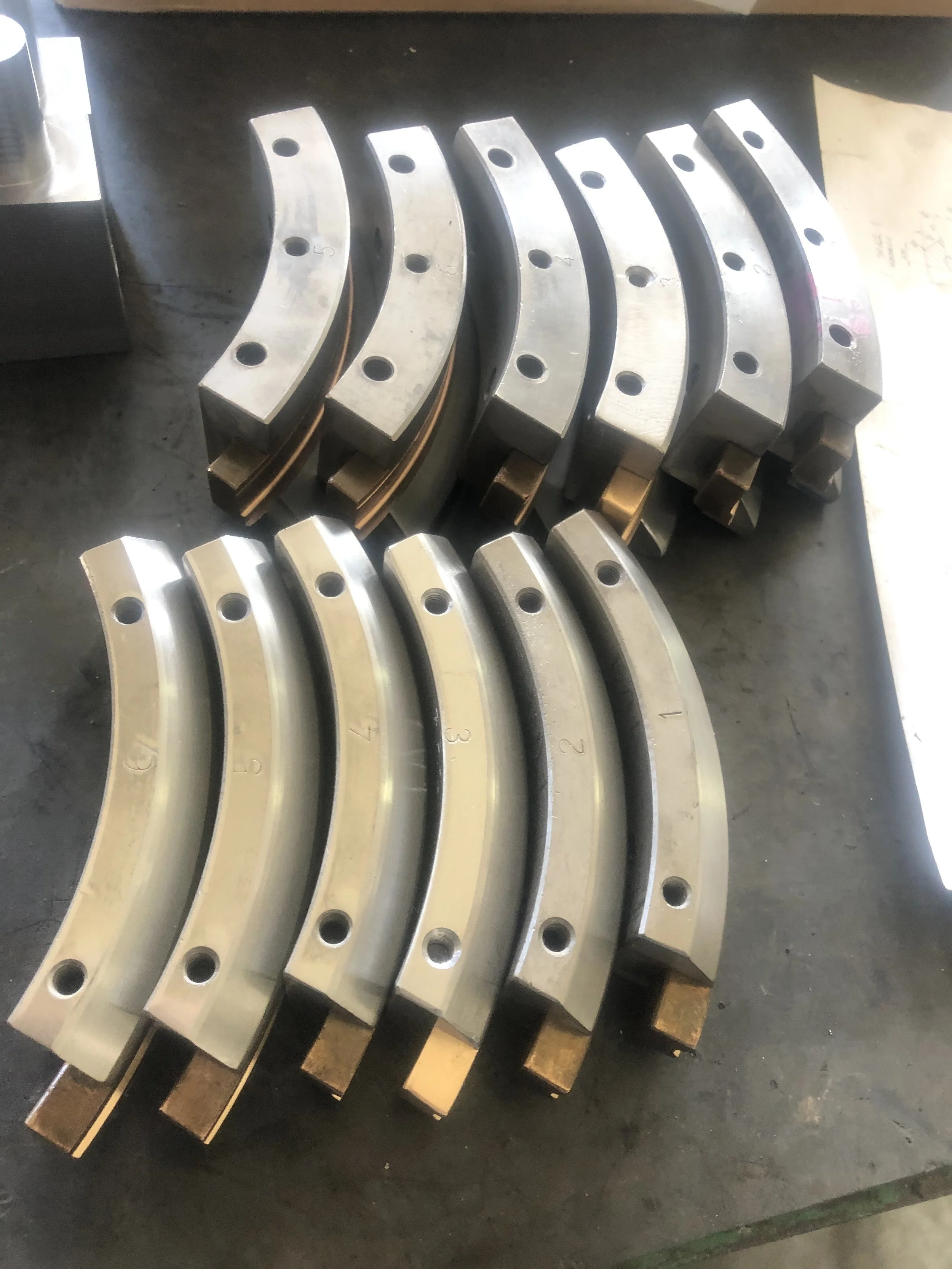 Set di bronzine di grandi dimensioni, rivestite di metallo, con fori di fissaggio, disposte su una superficie di lavoro.