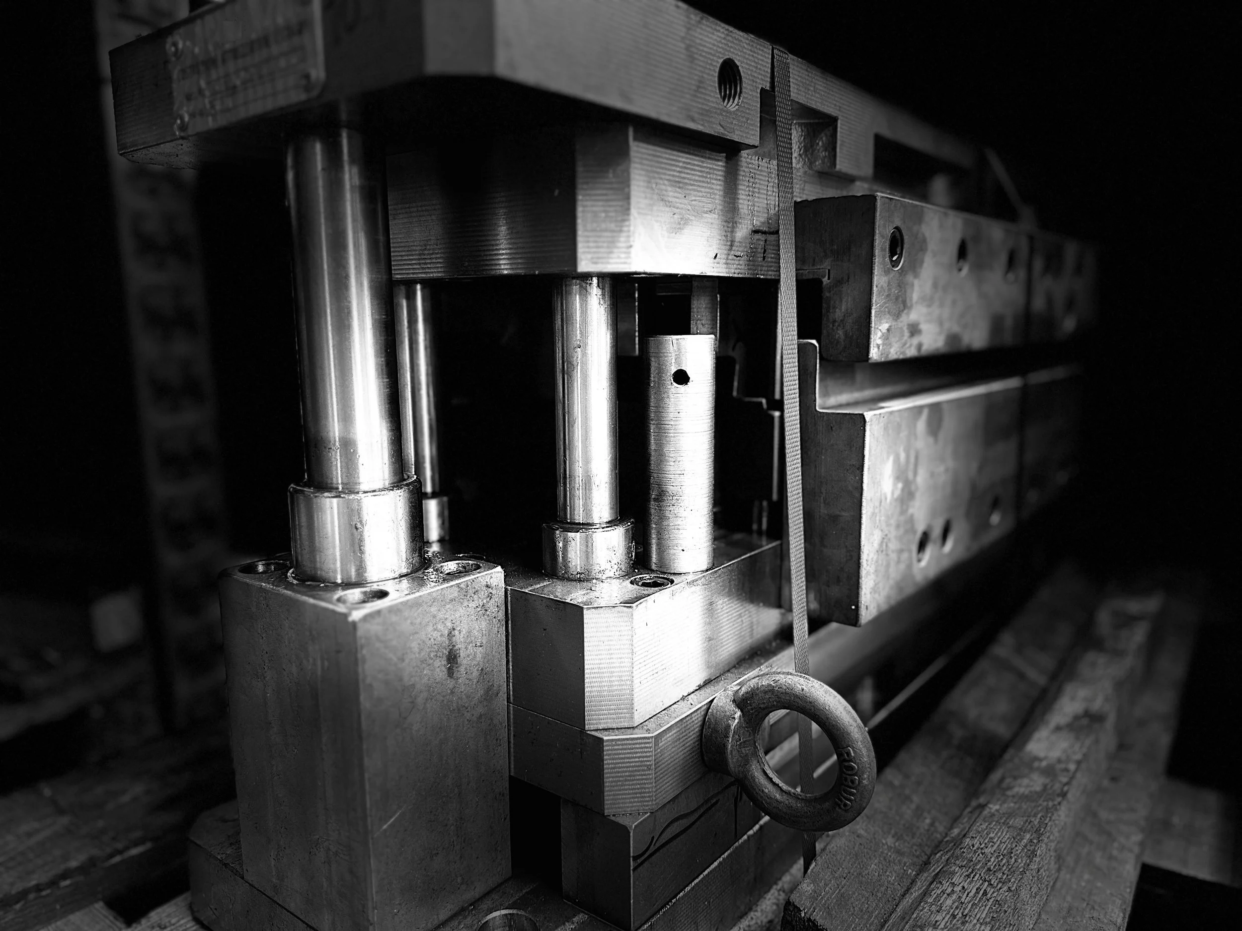 Immagine in bianco e nero di un complesso meccanico con cilindri metallici e parti in metallo, probabilmente parte di una macchina industriale o di un attrezzo da officina.