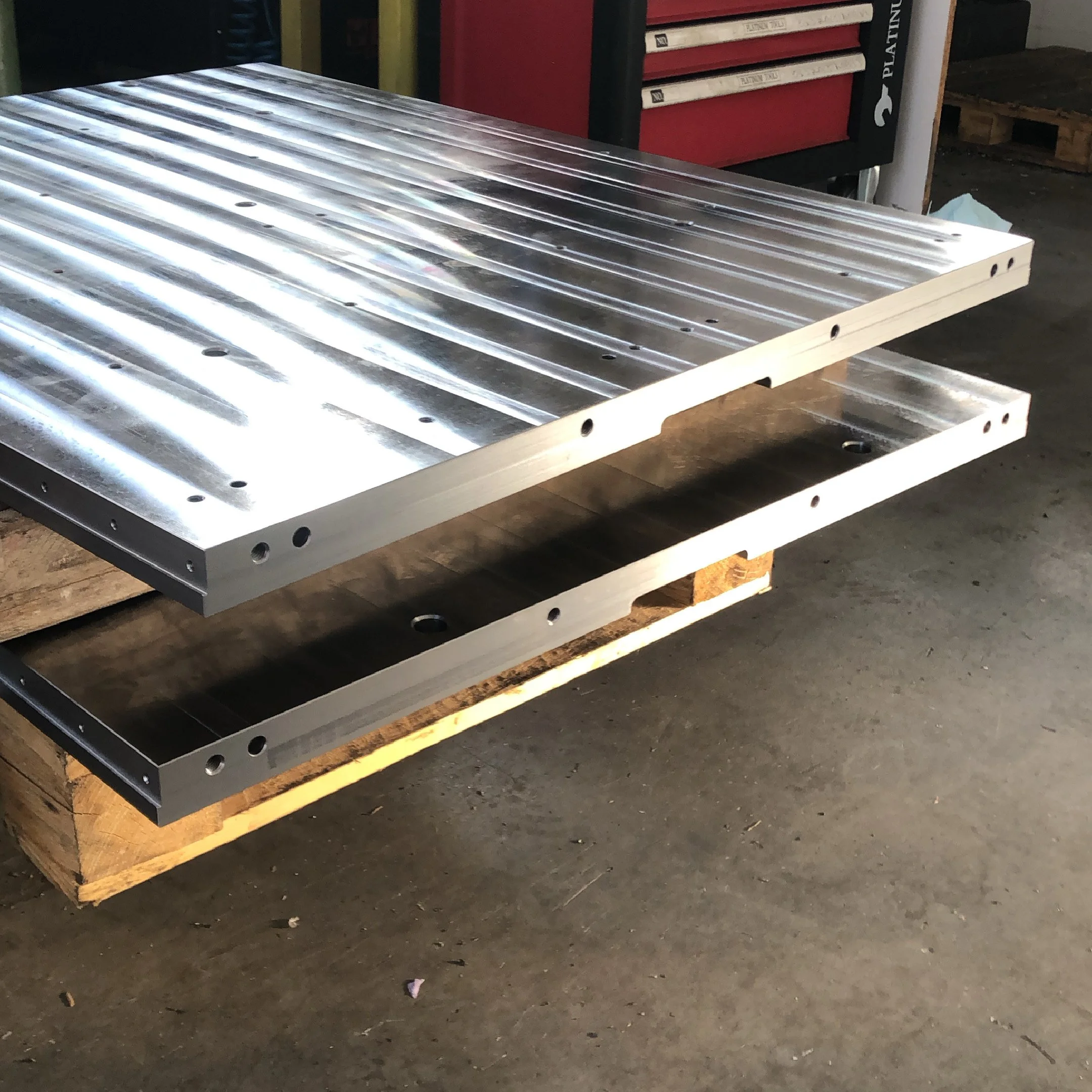 Due pannelli di metallo con scanalature su una superficie di legno, probabilmente parti di una macchina o attrezzatura industriale.