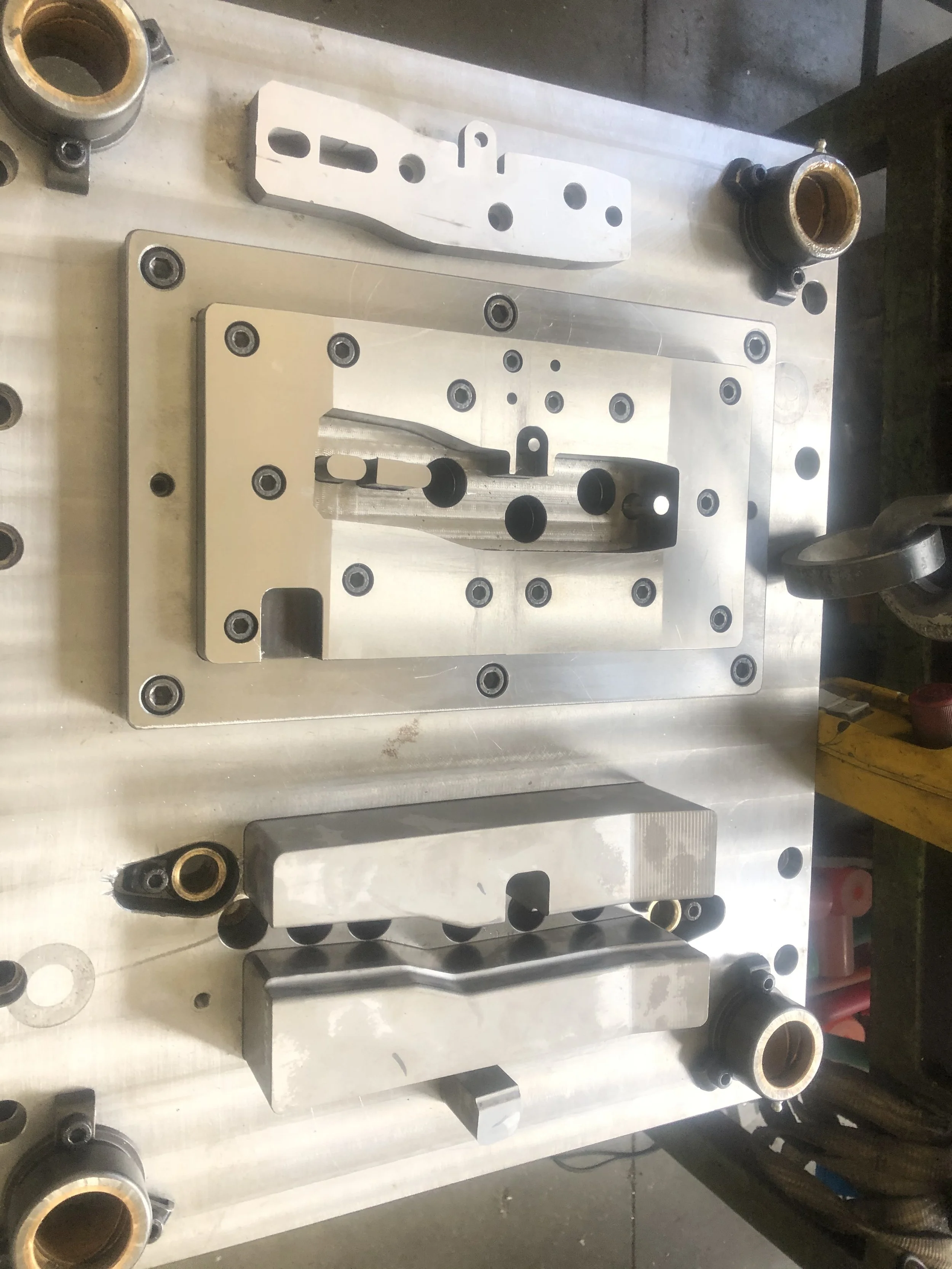 Parti metallici e componenti meccanici disposti su un tavolo in un'officina.