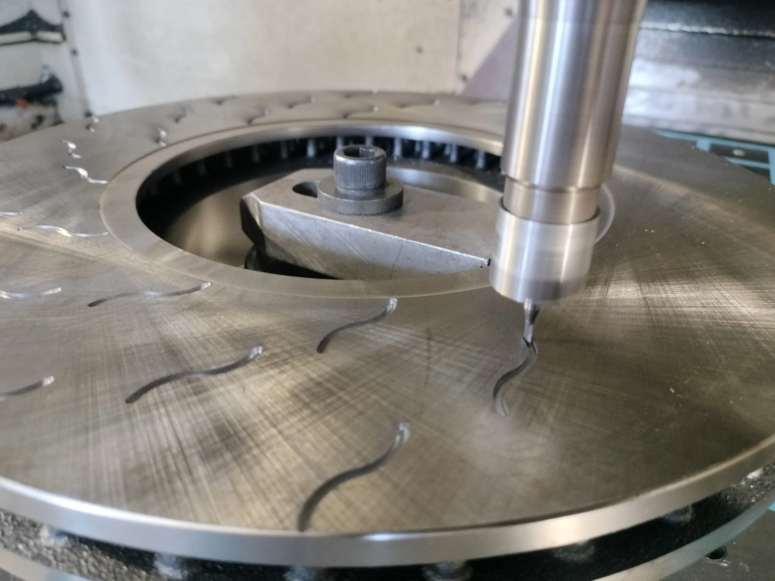 Una macchina utensile con un fresa che lavora su una piastra in metallo, creando dei canali o scanalature