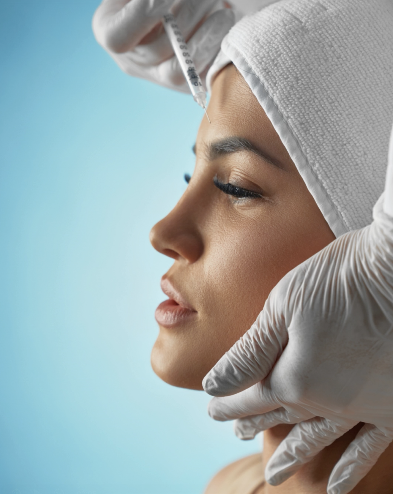 A woman is receiving a cosmetic injection in her forehead from a healthcare professional wearing latex gloves.