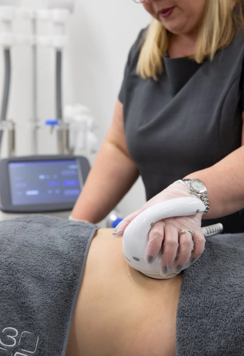 Medical professional performs ultrasound scan on a patient's abdomen using a handheld device in a clinical setting.