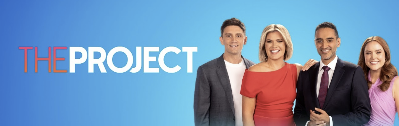Four people standing together smiling, with a blue background and the text 'The Project'.