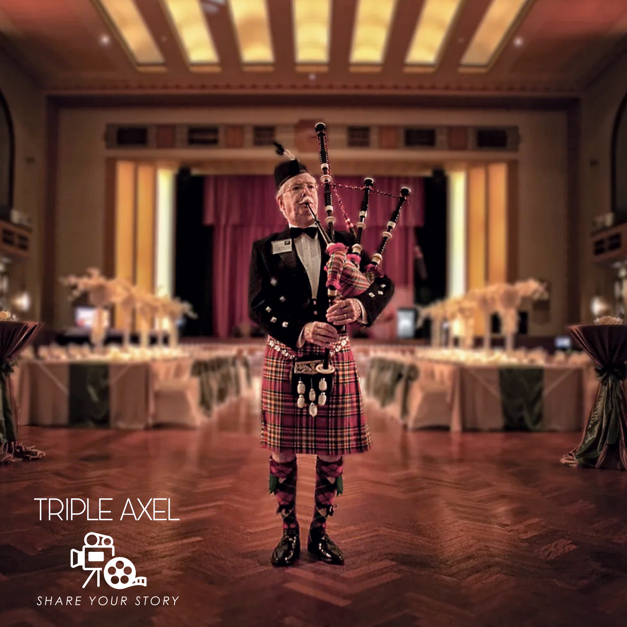 A man in a formal tuxedo playing the bagpipes inside a large, elegant hall with wooden floors, ornate ceilings, and a stage with red curtains.