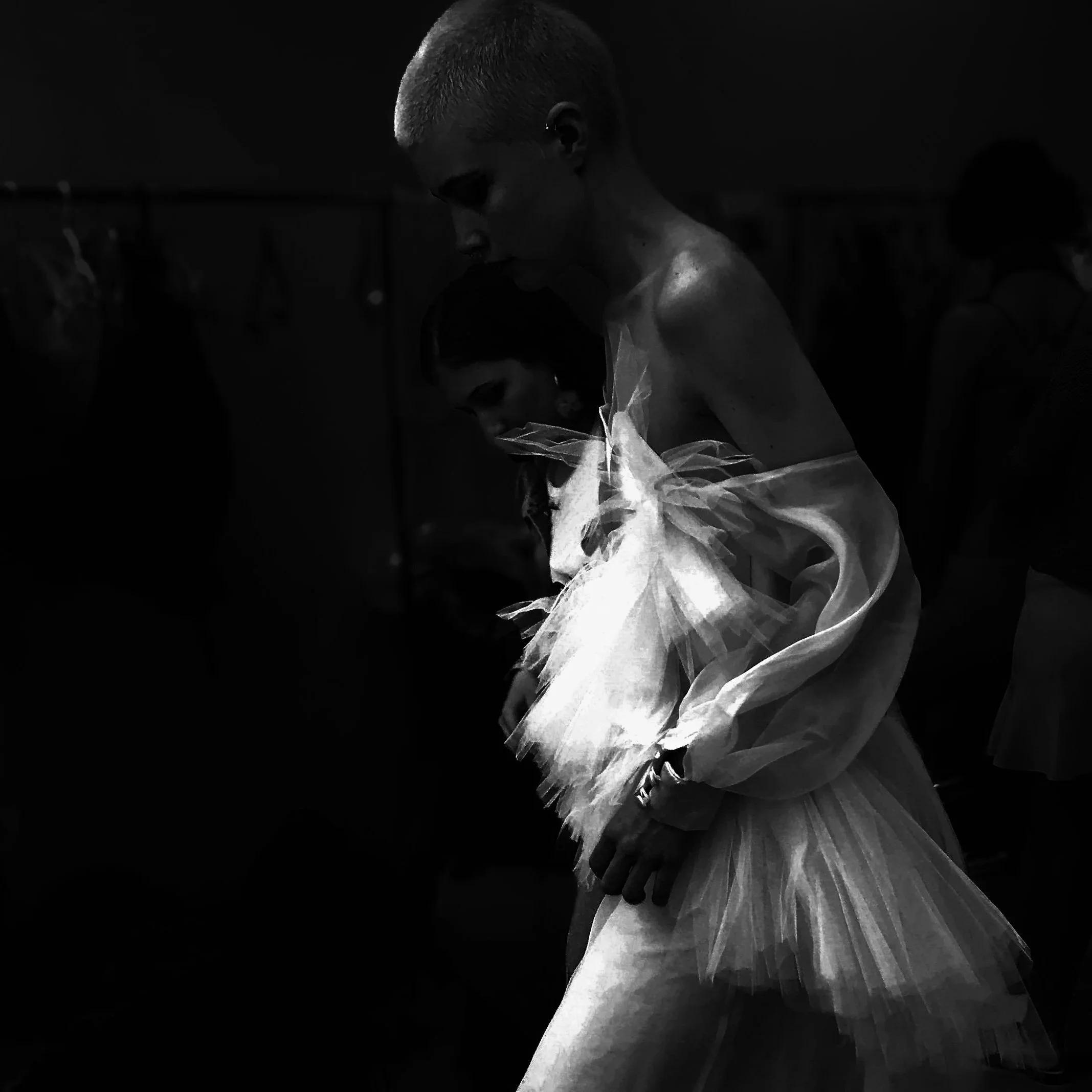 Black and white photo of a model wearing a tulle dress in a backstage area