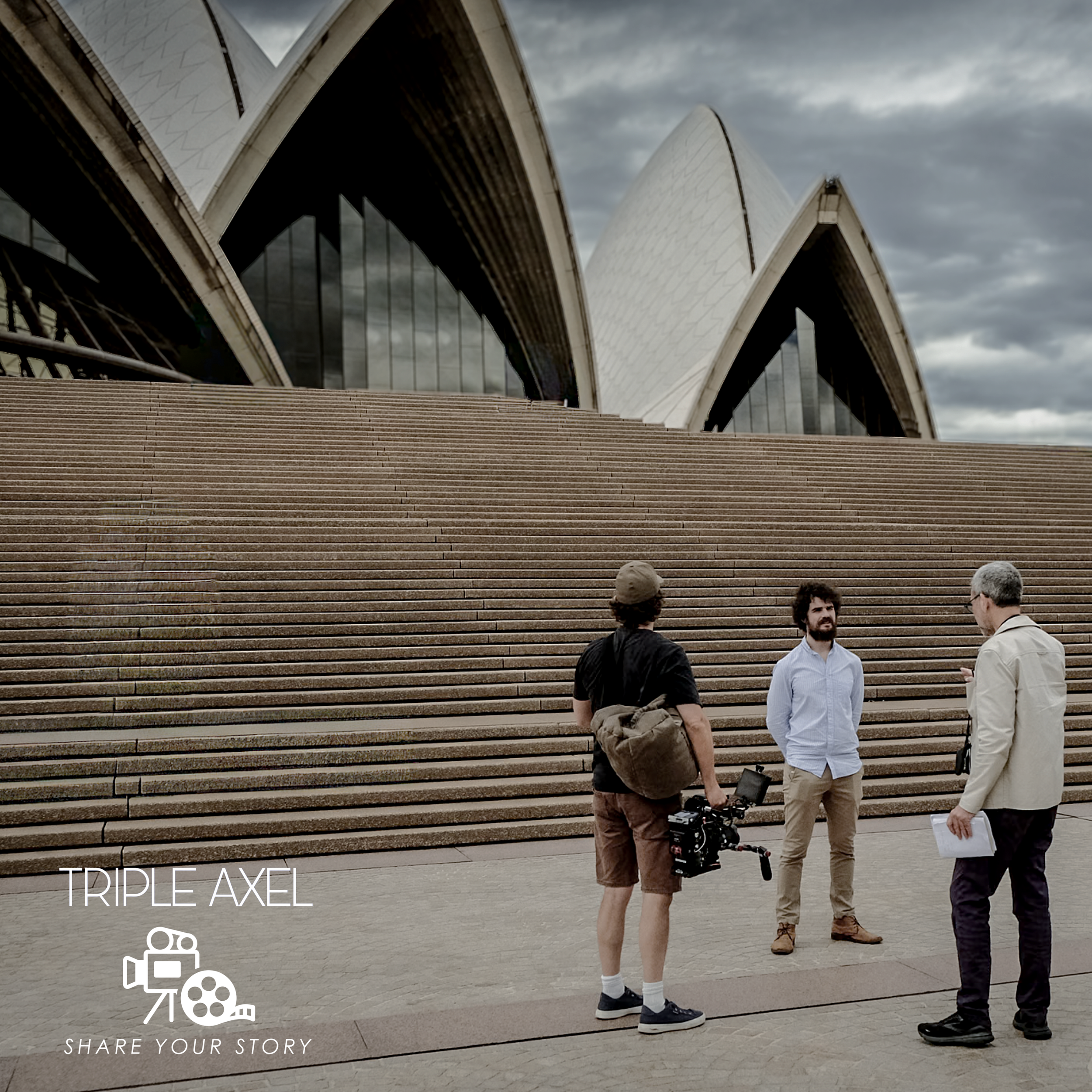 People standing on steps outside the Sydney Opera House under a cloudy sky, with some engaged in conversation and one person holding a camera.