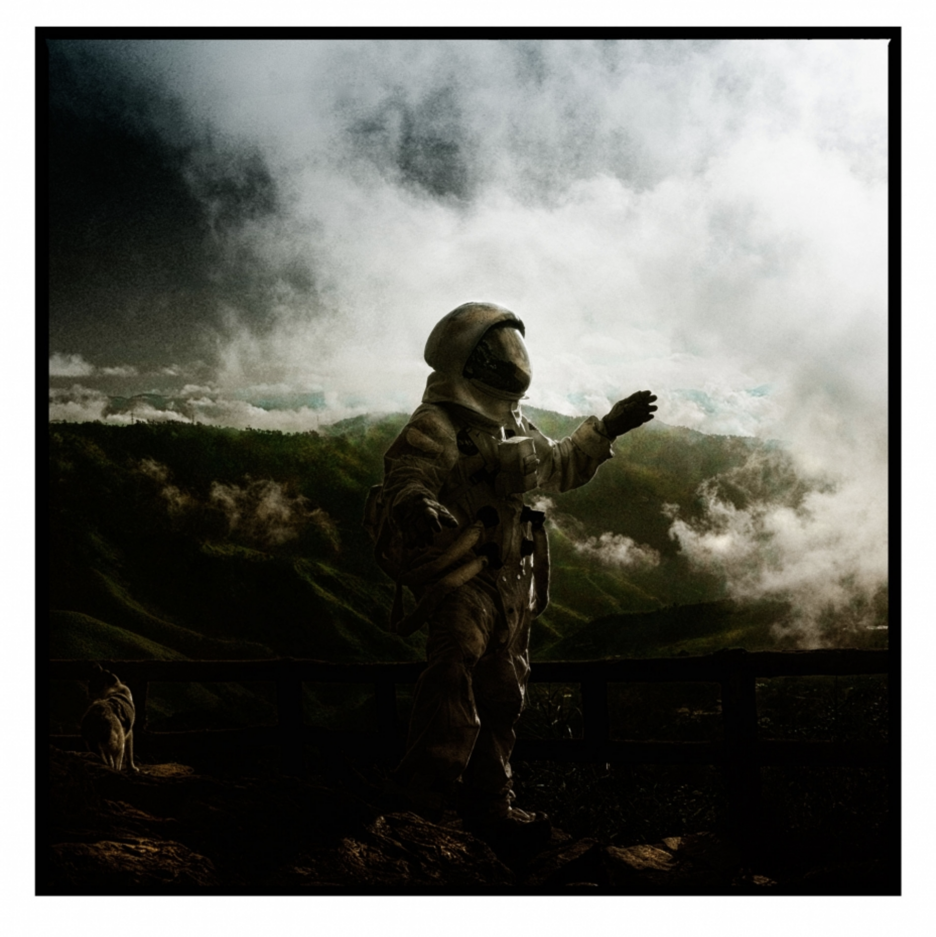 An astronaut in a spacesuit standing on a rugged terrain near a railing, with a mountainous landscape and cloudy sky in the background.
