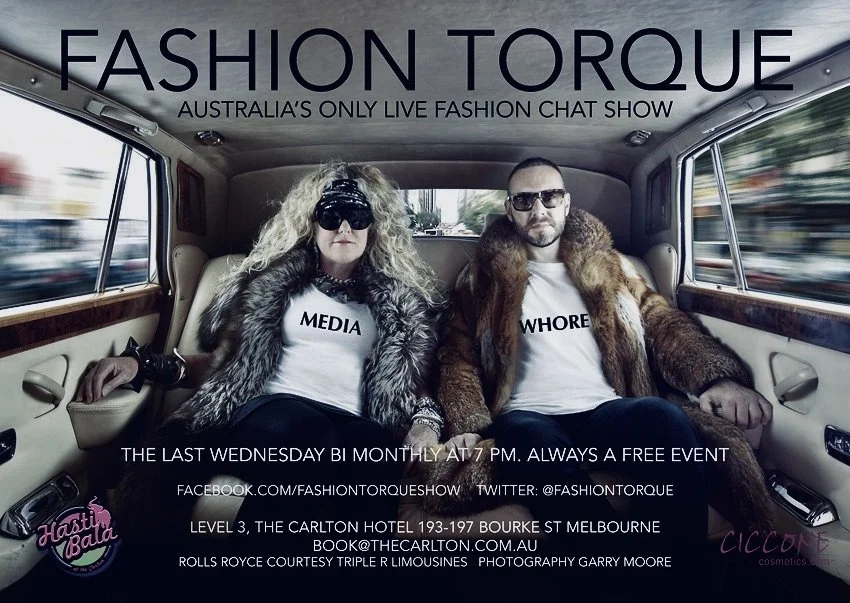 Two people wearing fur coats and graphic T-shirts sitting inside a vintage car. The woman’s shirt says 'MEDIA', and the man's shirt says 'WHORE'. They are advertising a fashion chat show event.