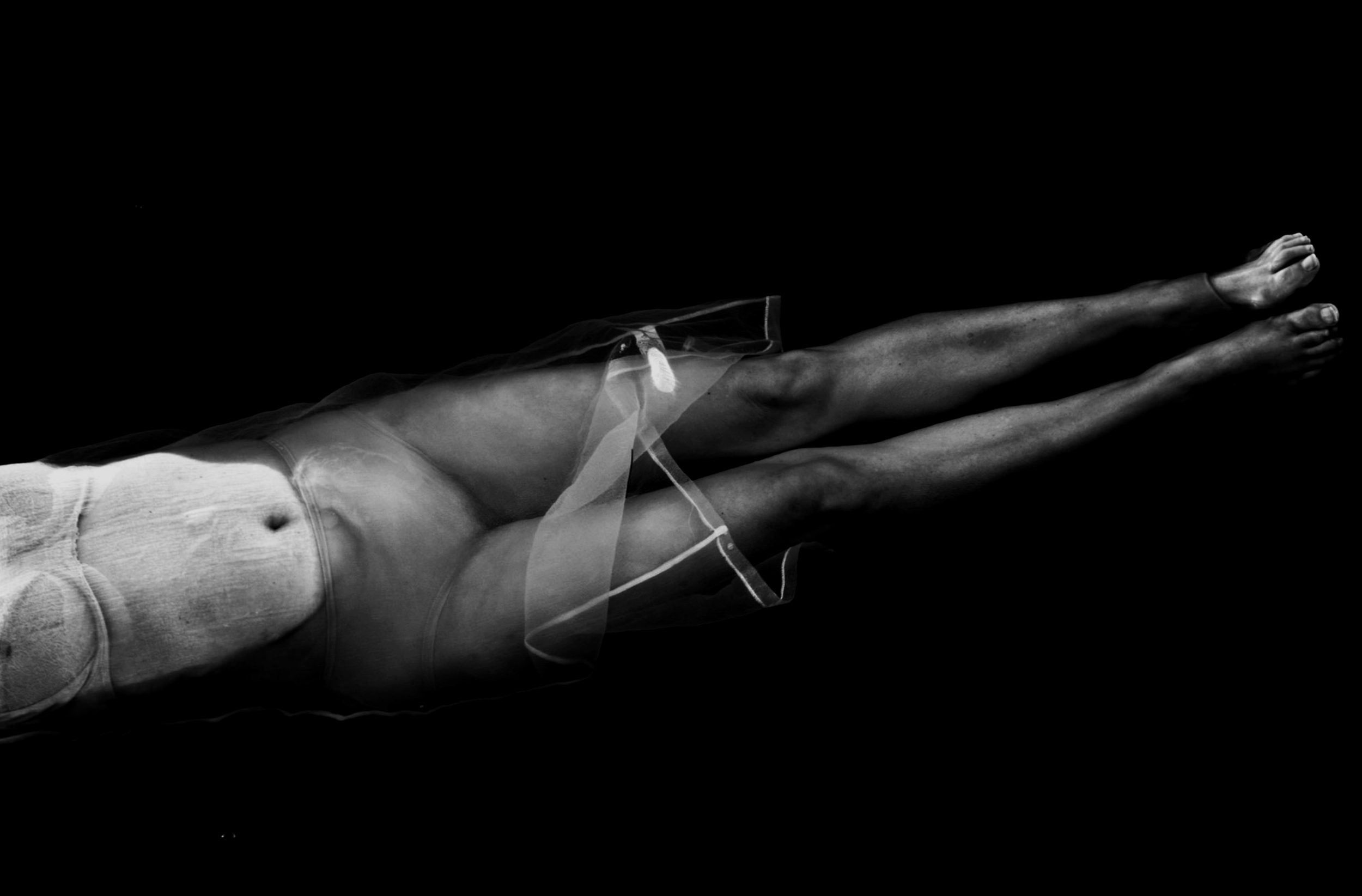 TRIPLE AXEL MEDIA
Premium Marketing Assets, Motion & Stills for Australian Education. Black and white photograph of a woman's body lying down, partially covered in sheer fabric, with a dark background.