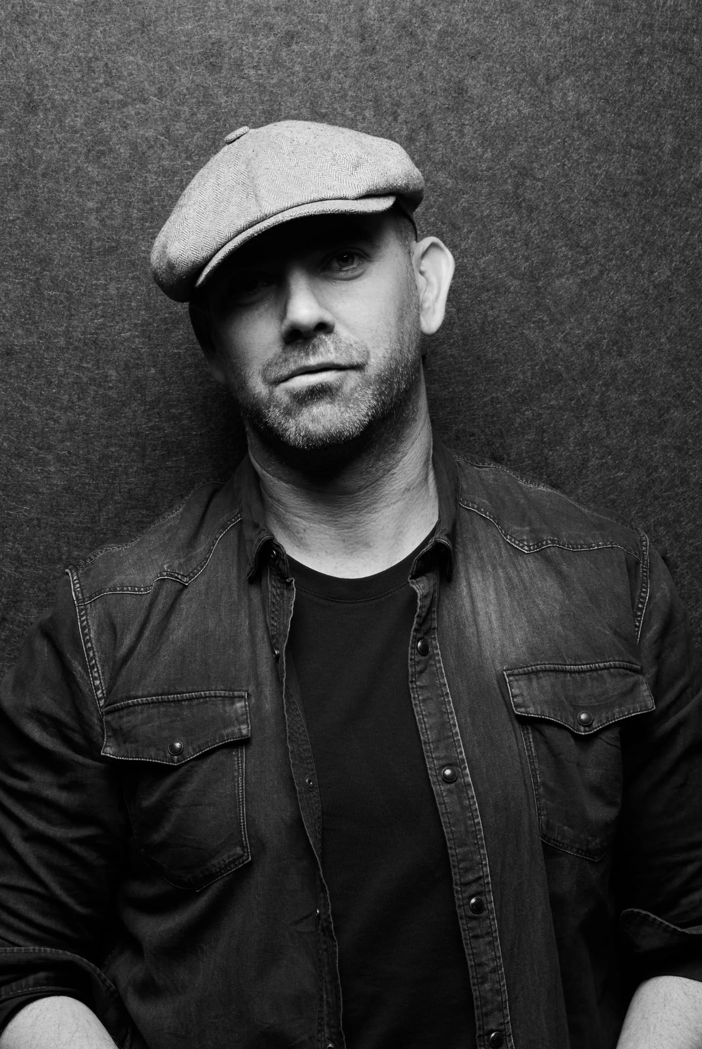 Explore TRIPLE AXEL - a revolutionary new platform designed to address talent retention, mentorship solutions and career resources. A uniquBlack and white portrait of a man wearing a flat cap and a denim shirt, standing against a textured background.