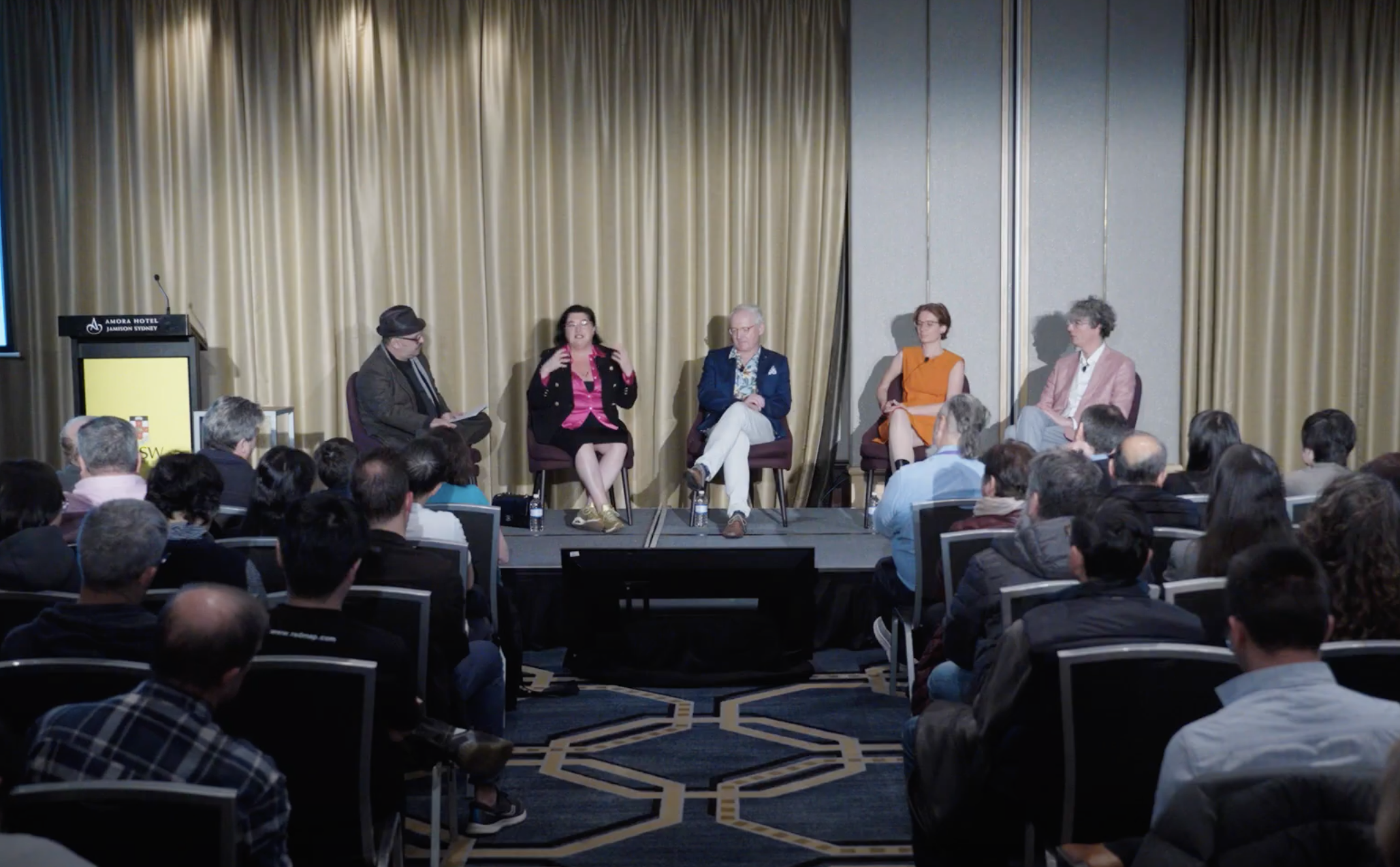 Explore TRIPLE AXEL - a revolutionary new platform designed to address talent retention, mentorship soA panel discussion at a conference with five people on stage, four women and one man, speaking and listening to each other, in front of an audience.