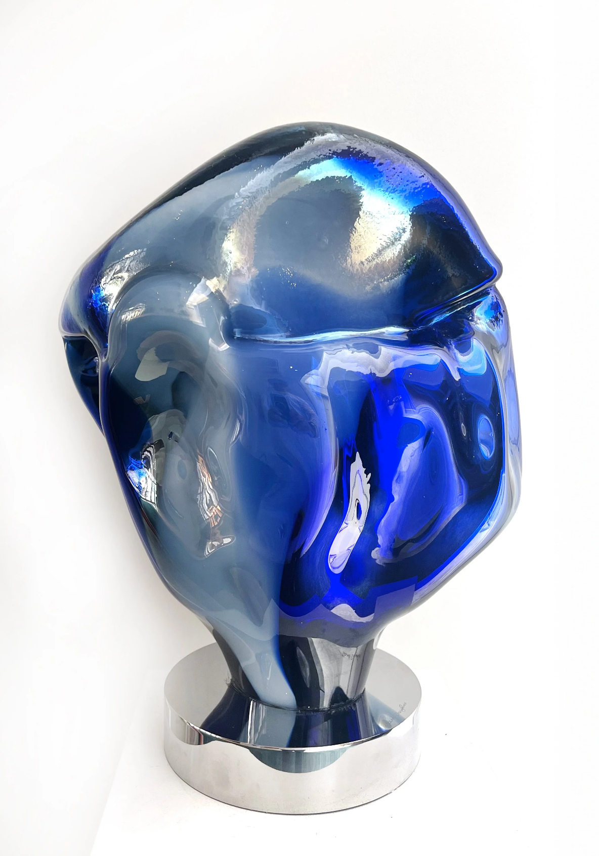 A modern art sculpture with swirling blue, silver, and black colors on a metallic base.