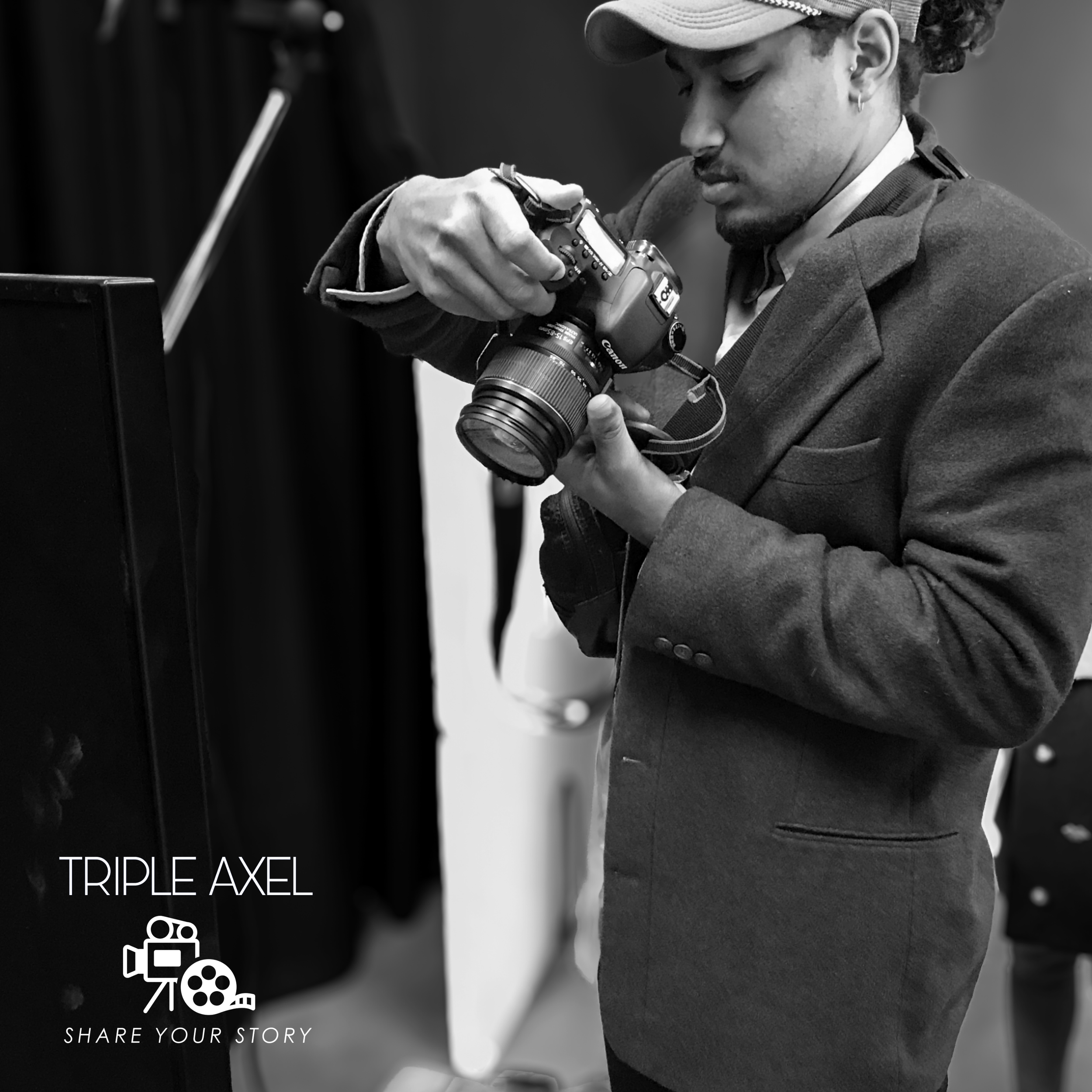 A person wearing a cap and jacket, looking down at a camera. The scene is in black and white. There is white text and icons in the bottom left corner that say "TRIPLE AXEL" and "SHARE YOUR STORY" with film and video icons.