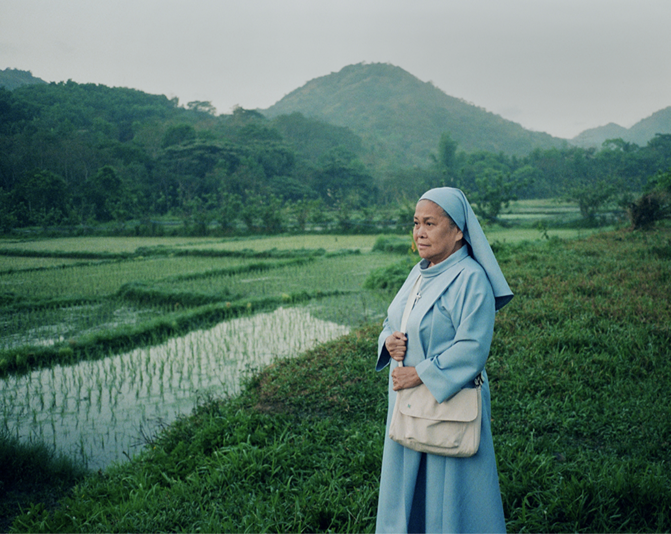 Explore TRIPLE AXEL - a revolutionary new platform designed to address talent retention, mentorship solutions and career resources. A uniA nun in a light blue habit stands outdoors near rice paddies with lush green fields and hills in the background.
