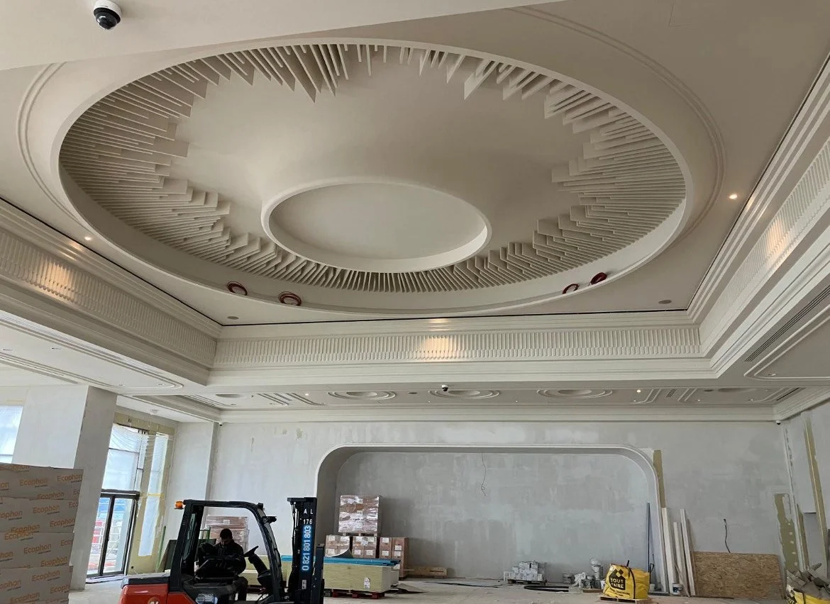 Plafond décoratif en construction avec un design circulaire et des éléments en relief dans une salle en rénovation.