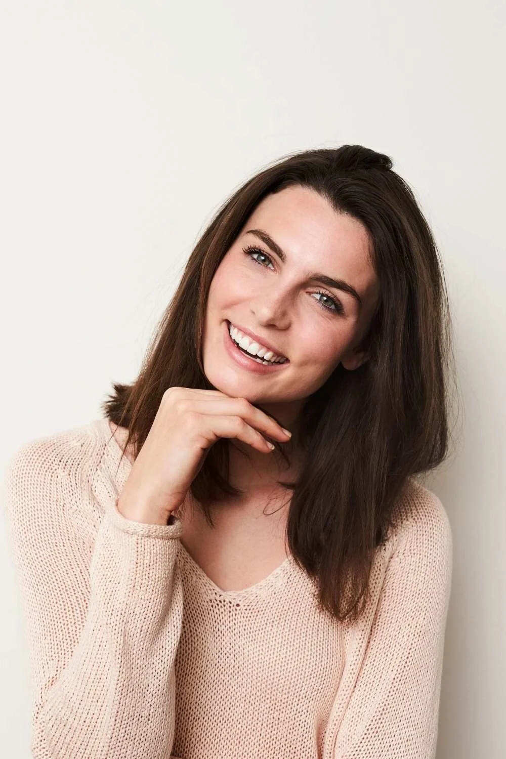 Woman with brown hair smiling after gummy smile treatment.