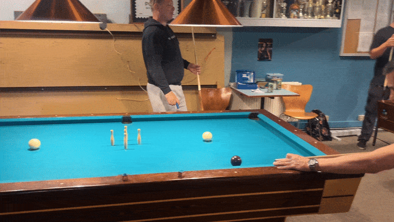 To personer spiller pool i et spil, hvor én person er ved kanten af poolbordet og den anden er ved den anden side.