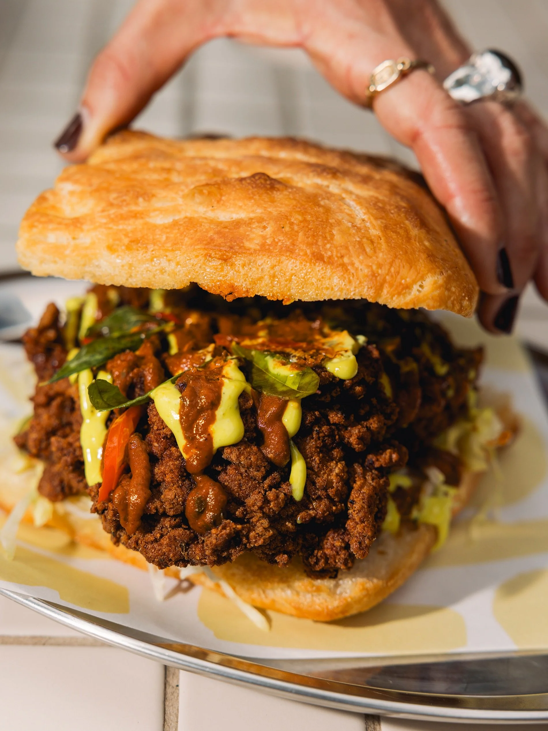 Our Fried Chicken Focaccia just got a glow up.

Keralan fried chicken, makhani ketchup, curry leaf aioli, dill pickles, lettuce and our house-made spd focaccia.

Crispy, spicy, tangy and impossible to put down. Availanle from 10am daily.